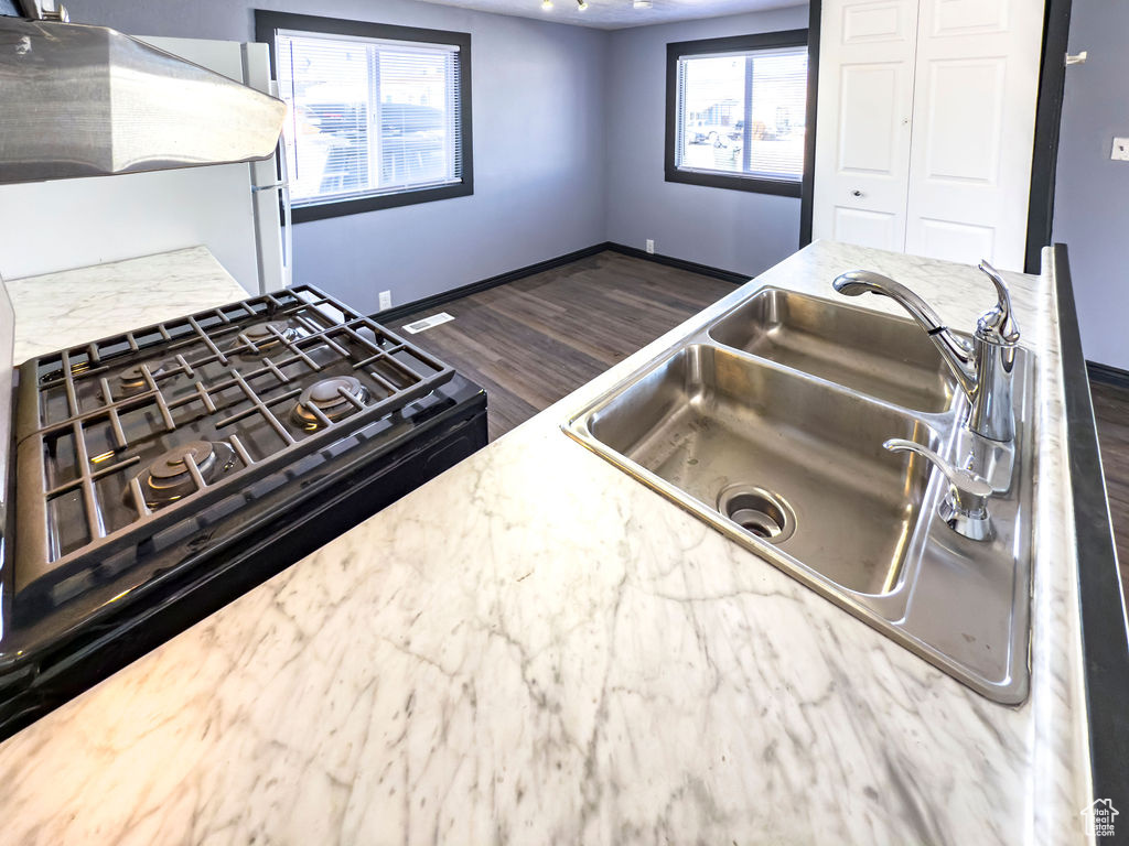 Kitchen featuring black gas range, sink, dark wood-type flooring, and white refrigerator