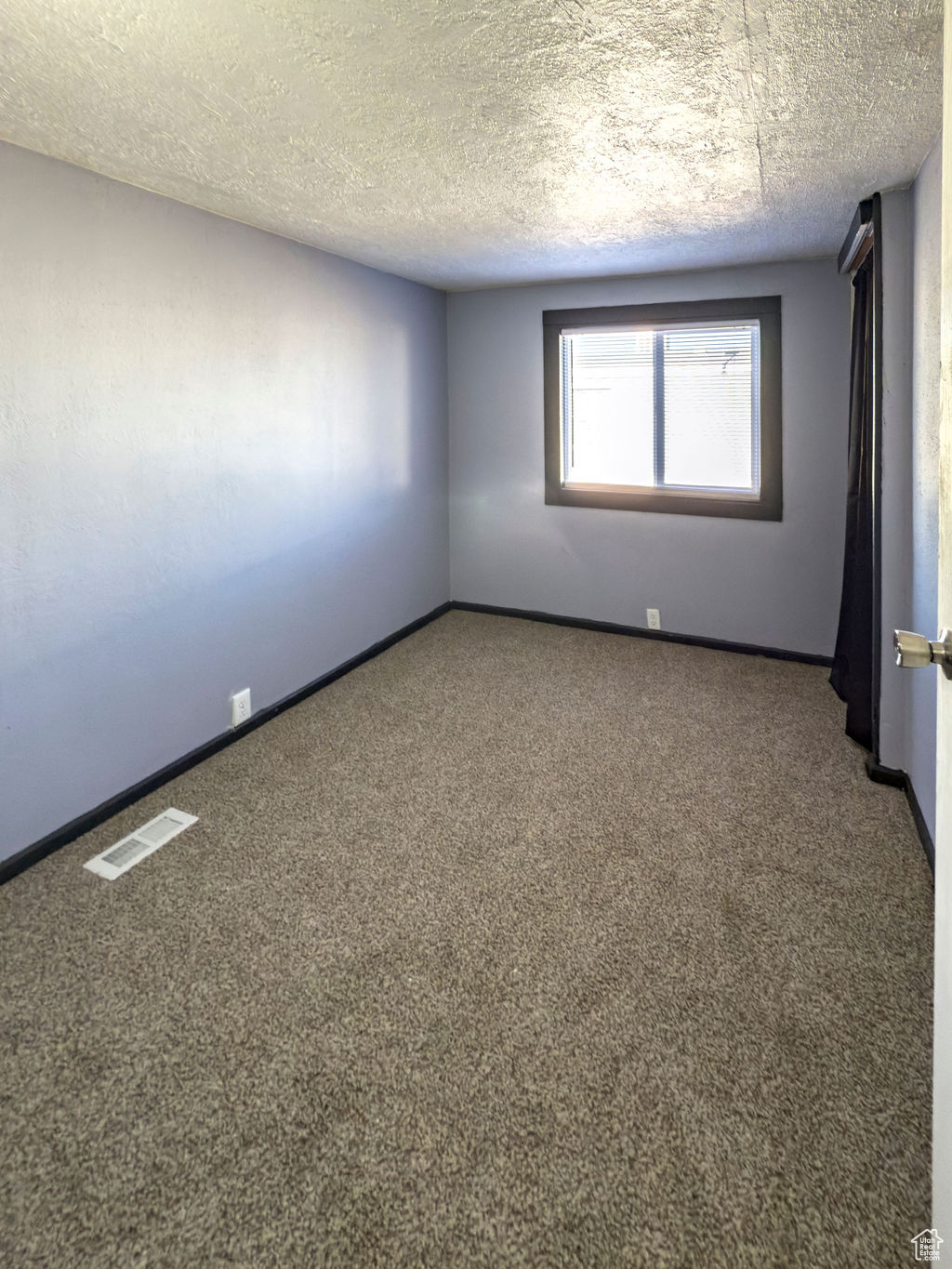 Carpeted spare room featuring a textured ceiling