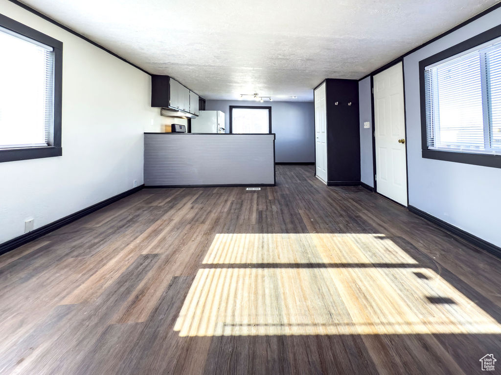 Unfurnished living room featuring dark wood-type flooring and a textured ceiling