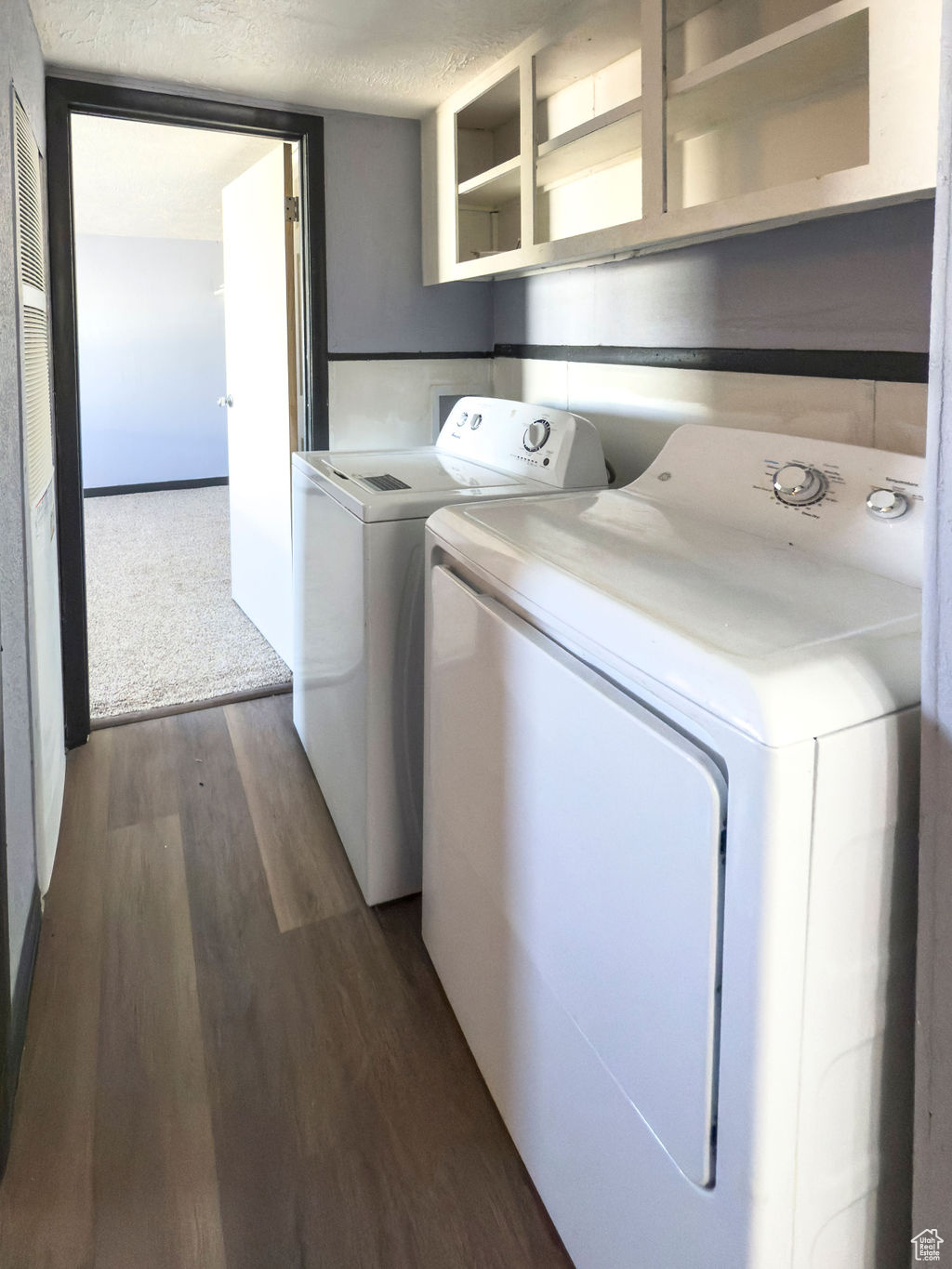 Washroom featuring dark wood-type flooring, separate washer and dryer, and a textured ceiling