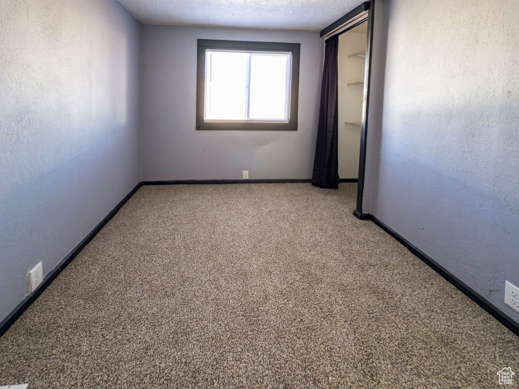Carpeted empty room featuring a textured ceiling