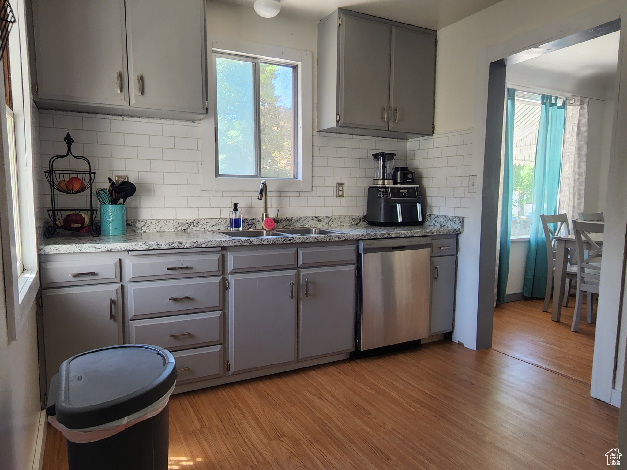 Kitchen featuring sink, light hardwood / wood-style flooring, stainless steel dishwasher, and gray cabinets