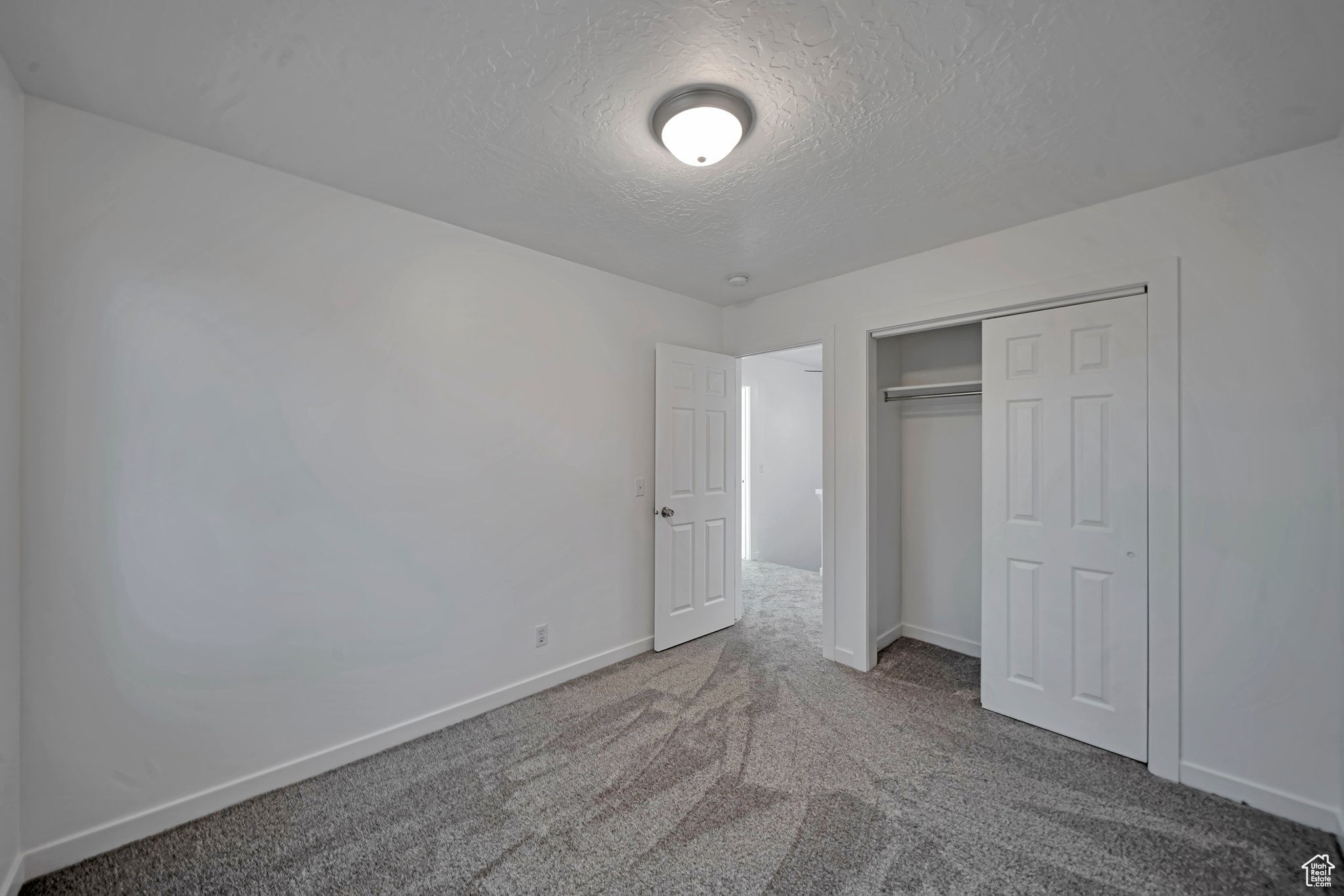 Unfurnished bedroom with carpet floors, a textured ceiling, and a closet