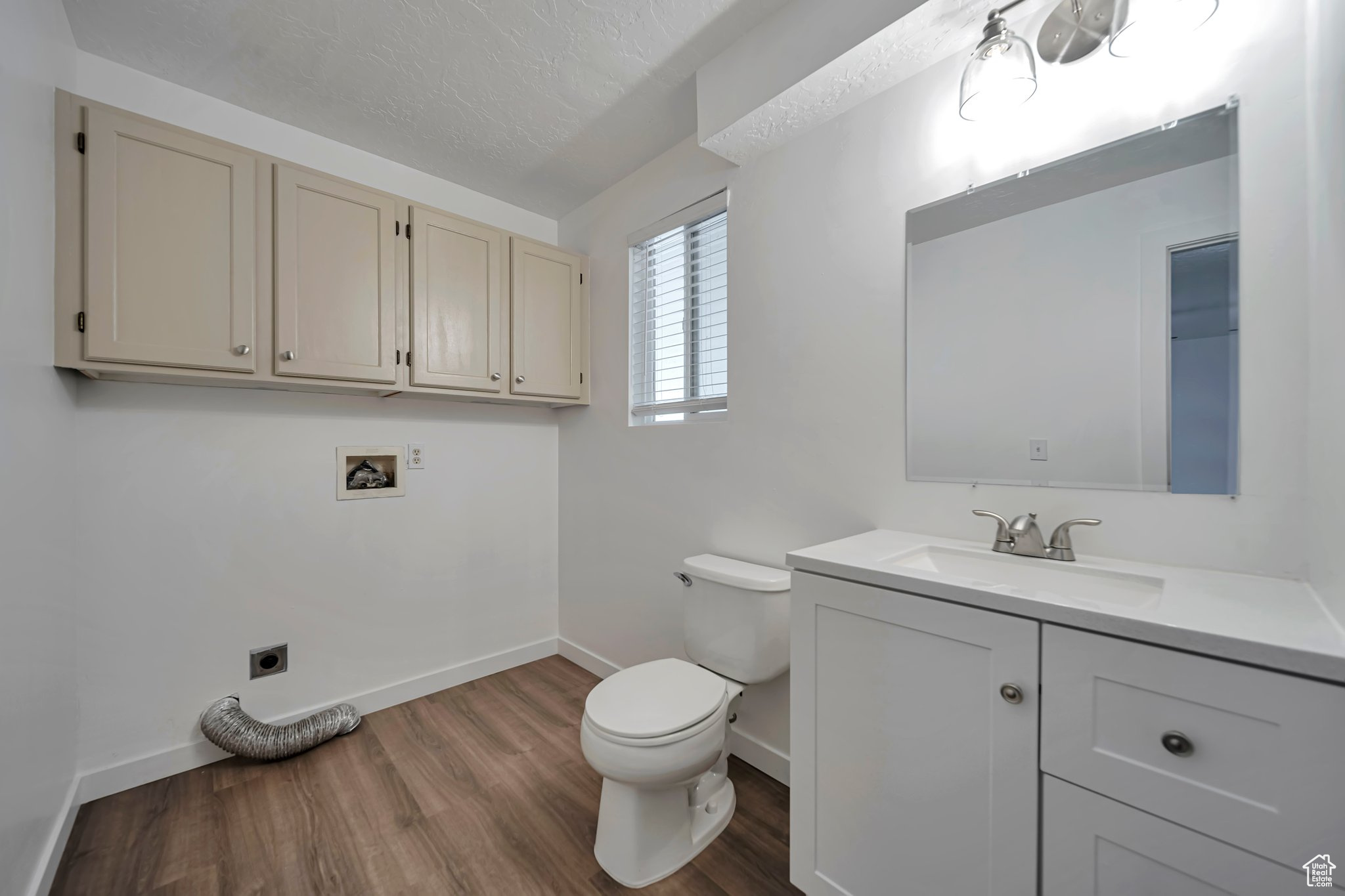 Bathroom featuring vanity, hardwood / wood-style floors, a textured ceiling, and toilet