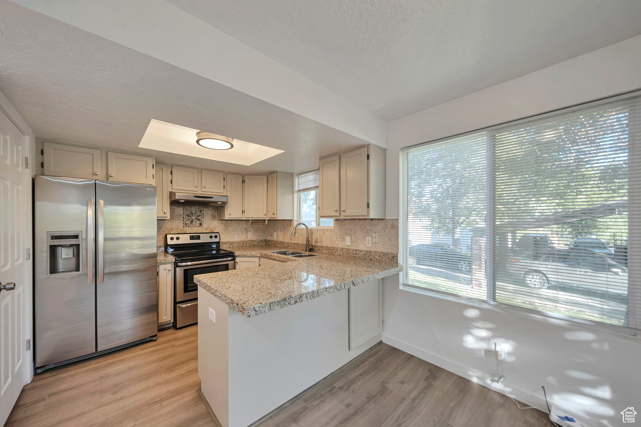 Kitchen with sink, backsplash, kitchen peninsula, and appliances with stainless steel finishes