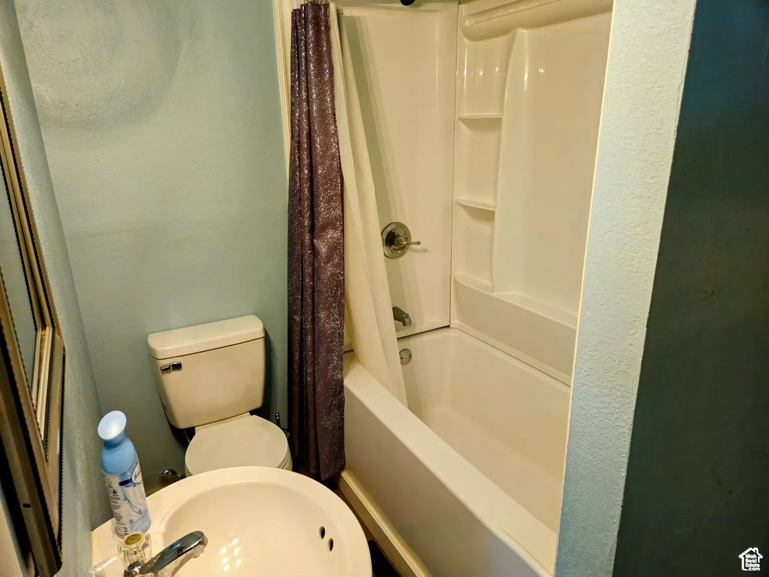 Full bathroom featuring sink, shower / bath combo with shower curtain, and toilet