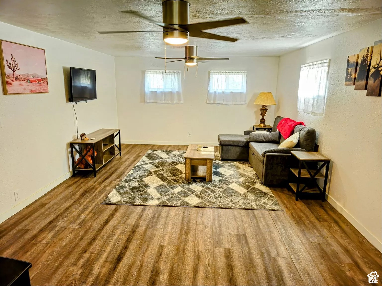 Living room featuring wood-type flooring, plenty of natural light, and a textured ceiling