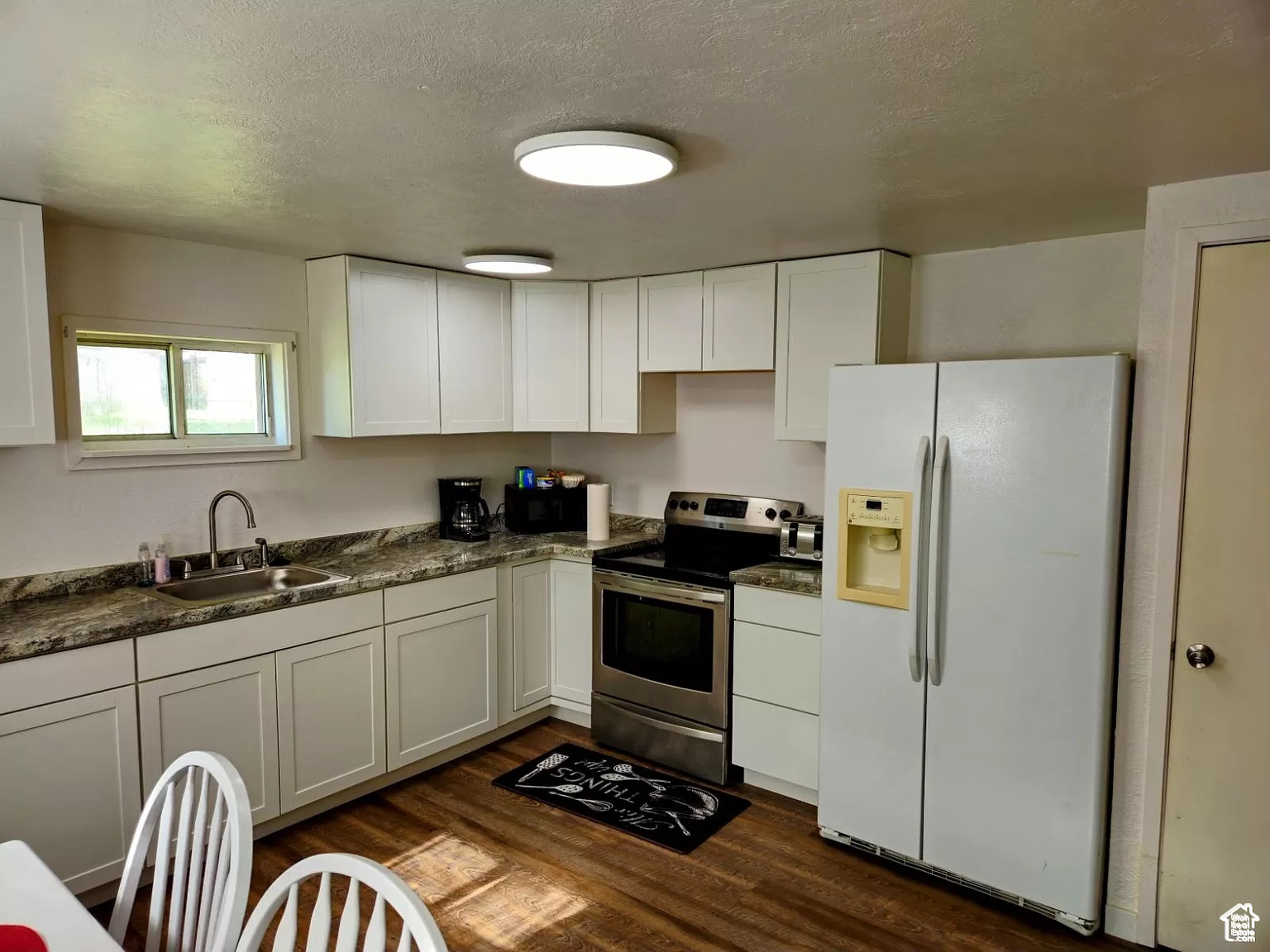 Kitchen featuring stainless steel range with electric stovetop, sink, white refrigerator with ice dispenser, and white cabinets