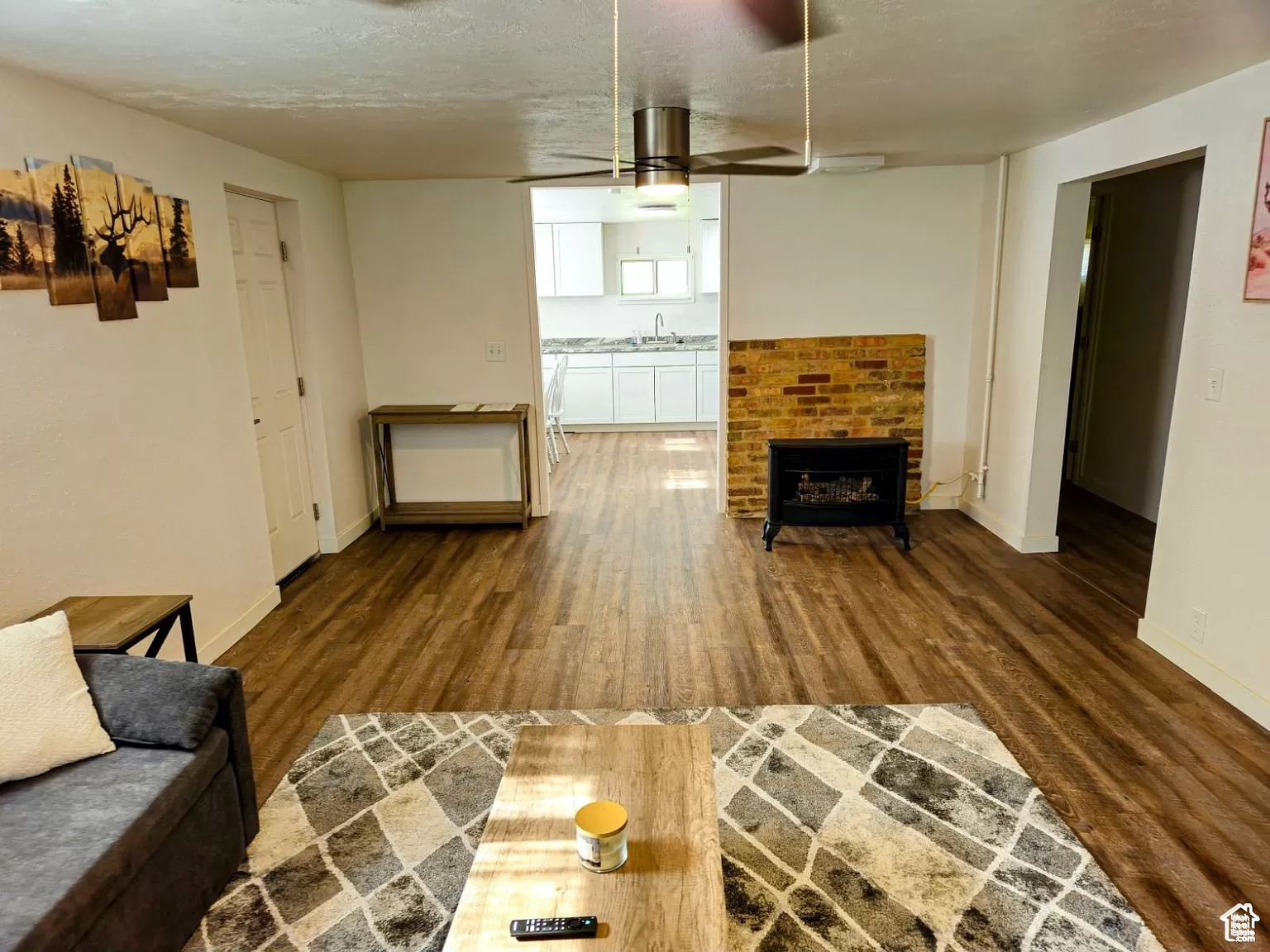 Living room featuring ceiling fan, sink, hardwood / wood-style floors, and a brick fireplace