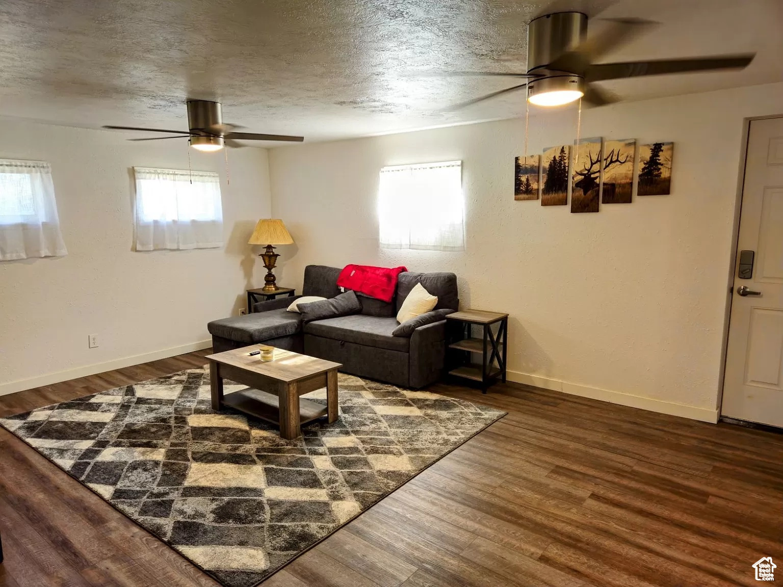 Living room with ceiling fan, dark hardwood / wood-style flooring, and a textured ceiling