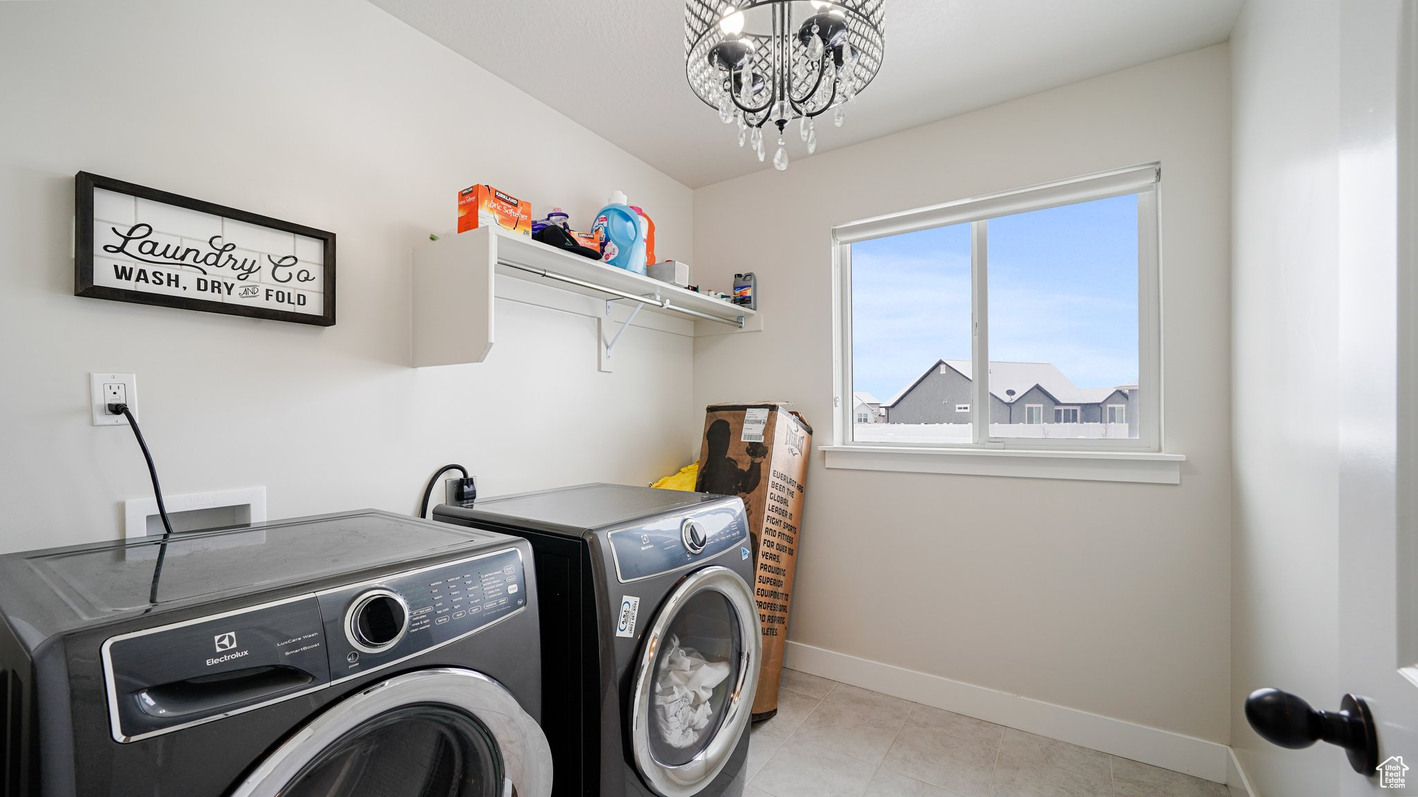Clothes washing area featuring light tile patterned floors, independent washer and dryer, and a chandelier