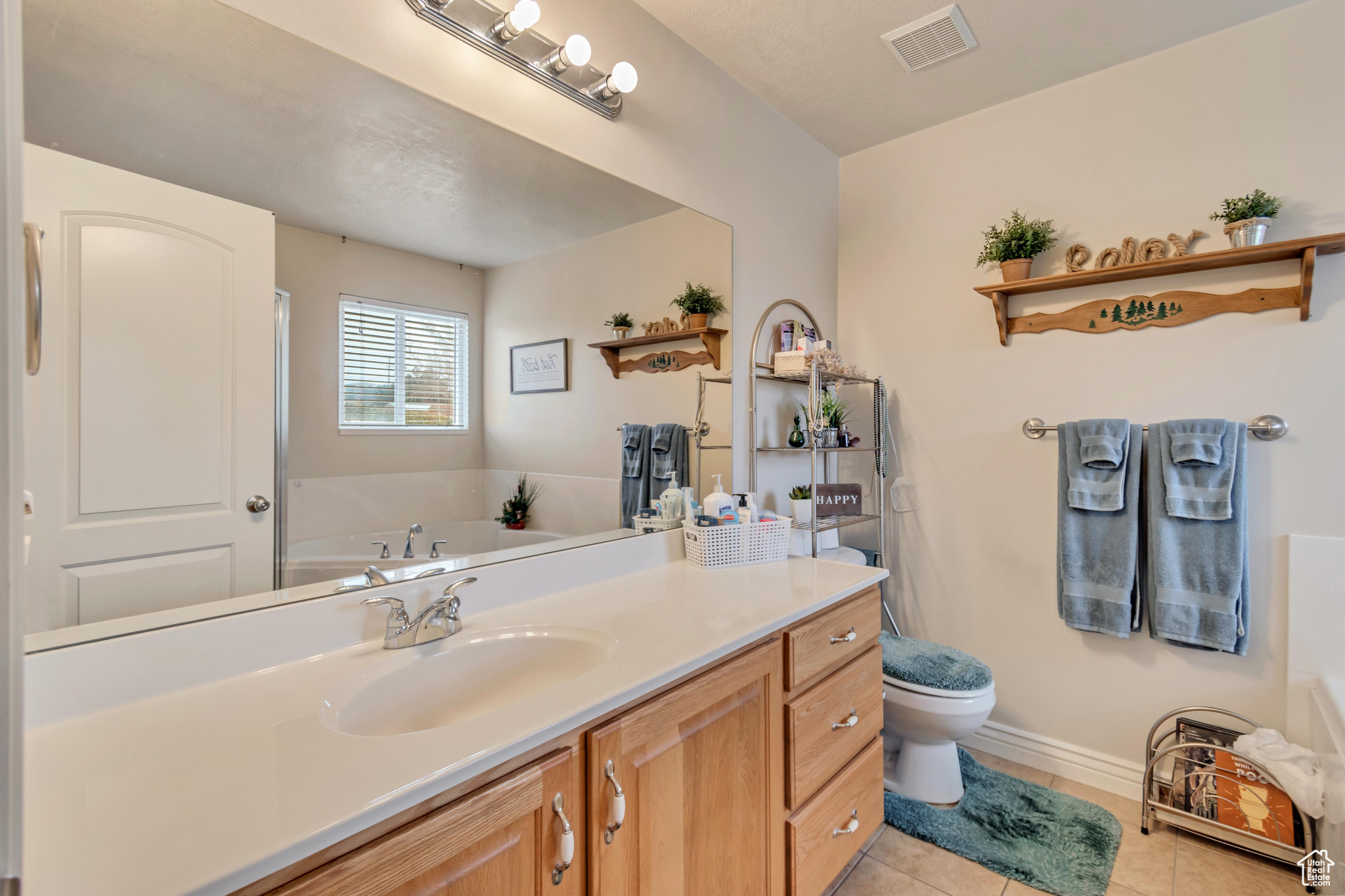 Master bathroom with tile flooring, vanity, a bath, and toilet