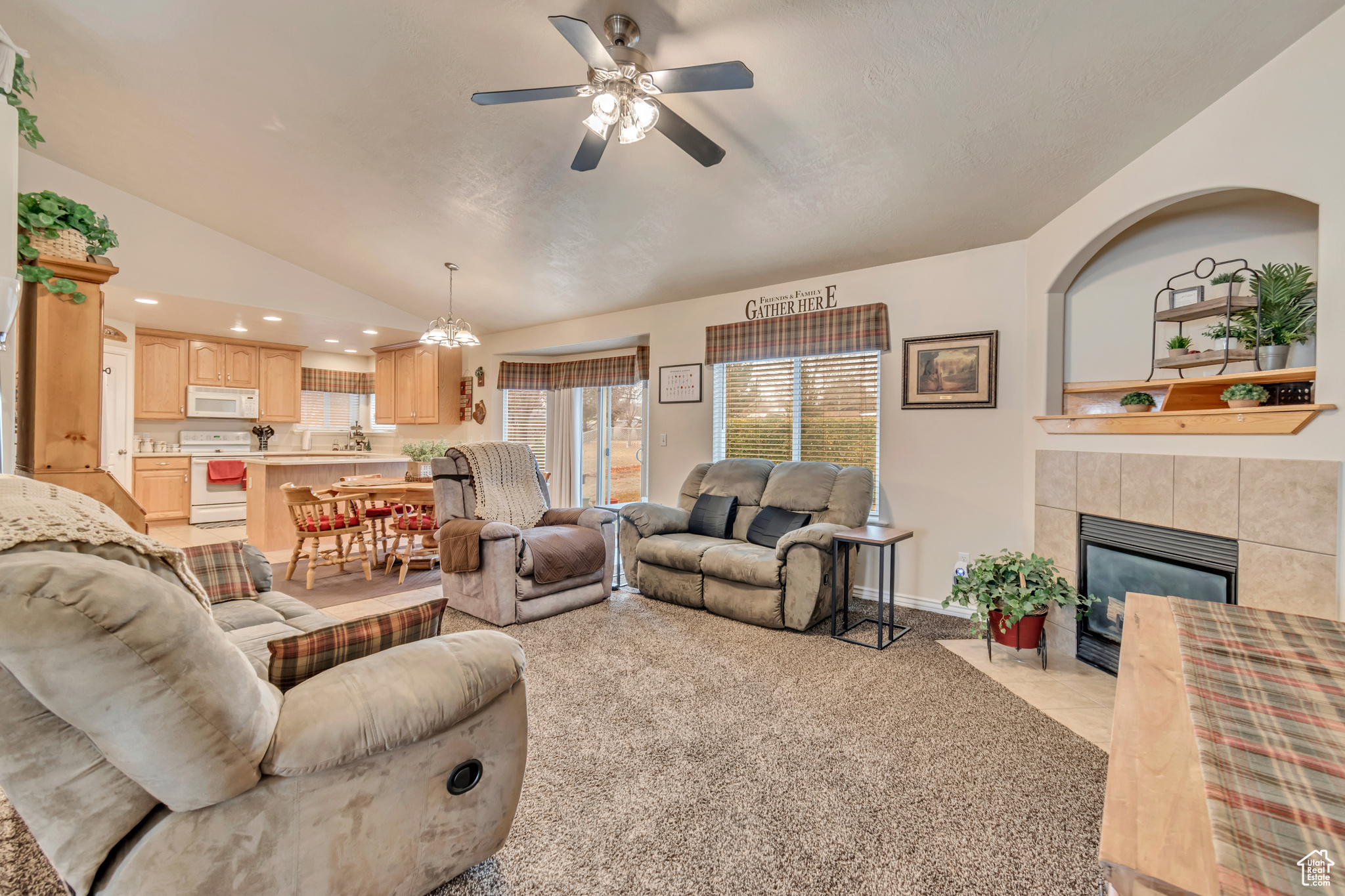 Family room featuring ceiling fan, lofted ceiling, a fireplace, and light carpet