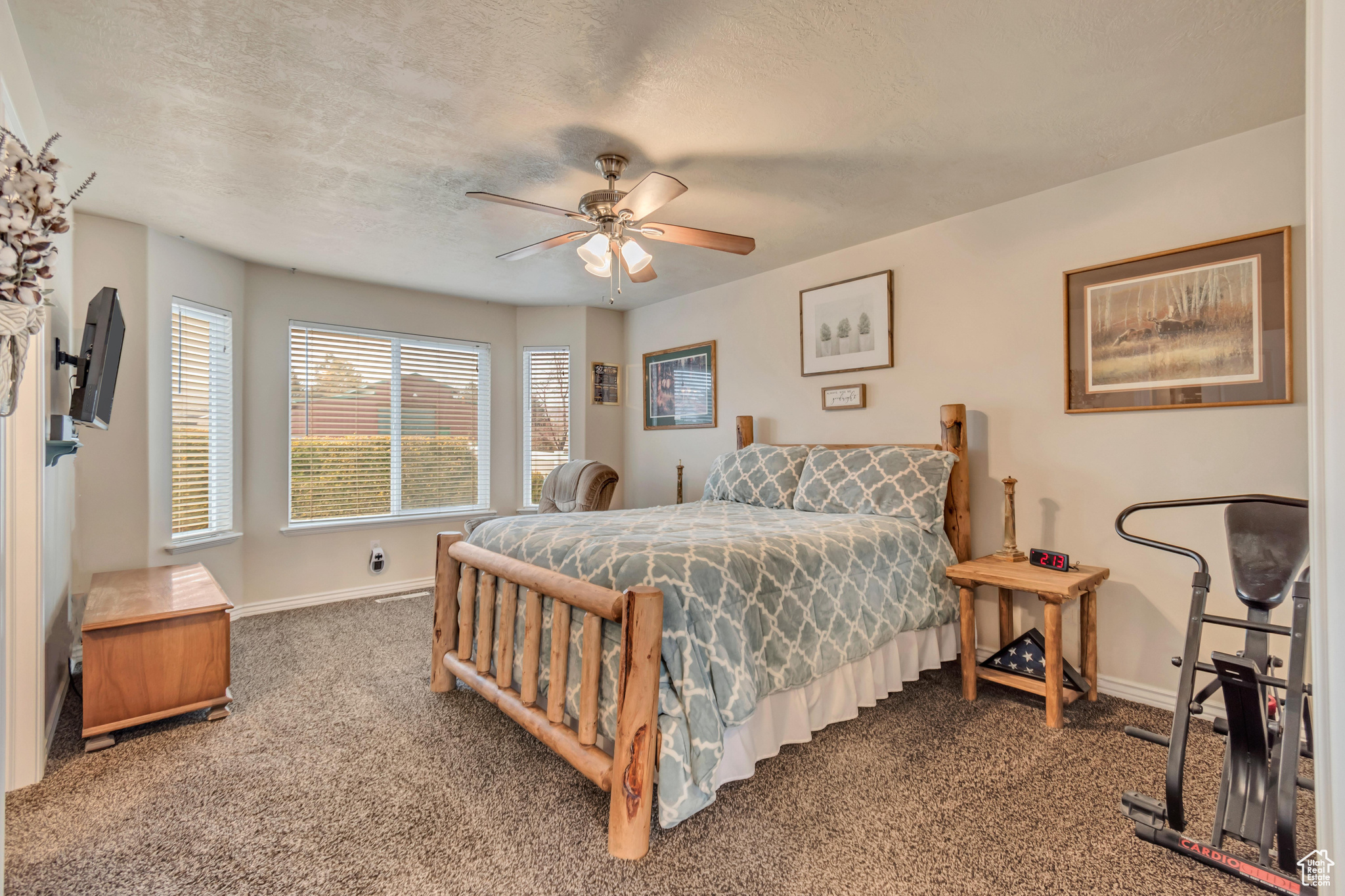 Master bedroom with ceiling fan, carpet floors, and a textured ceiling