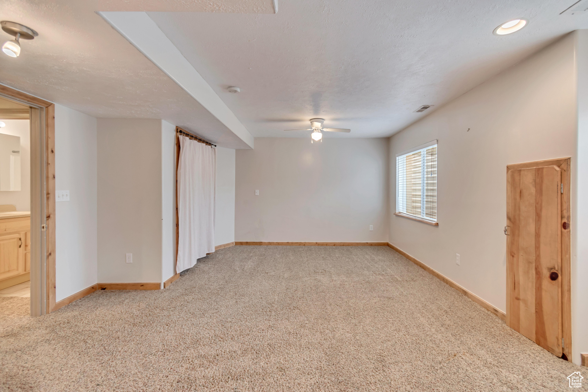 Large bedroom featuring ceiling fan, light colored carpet, and a textured ceiling