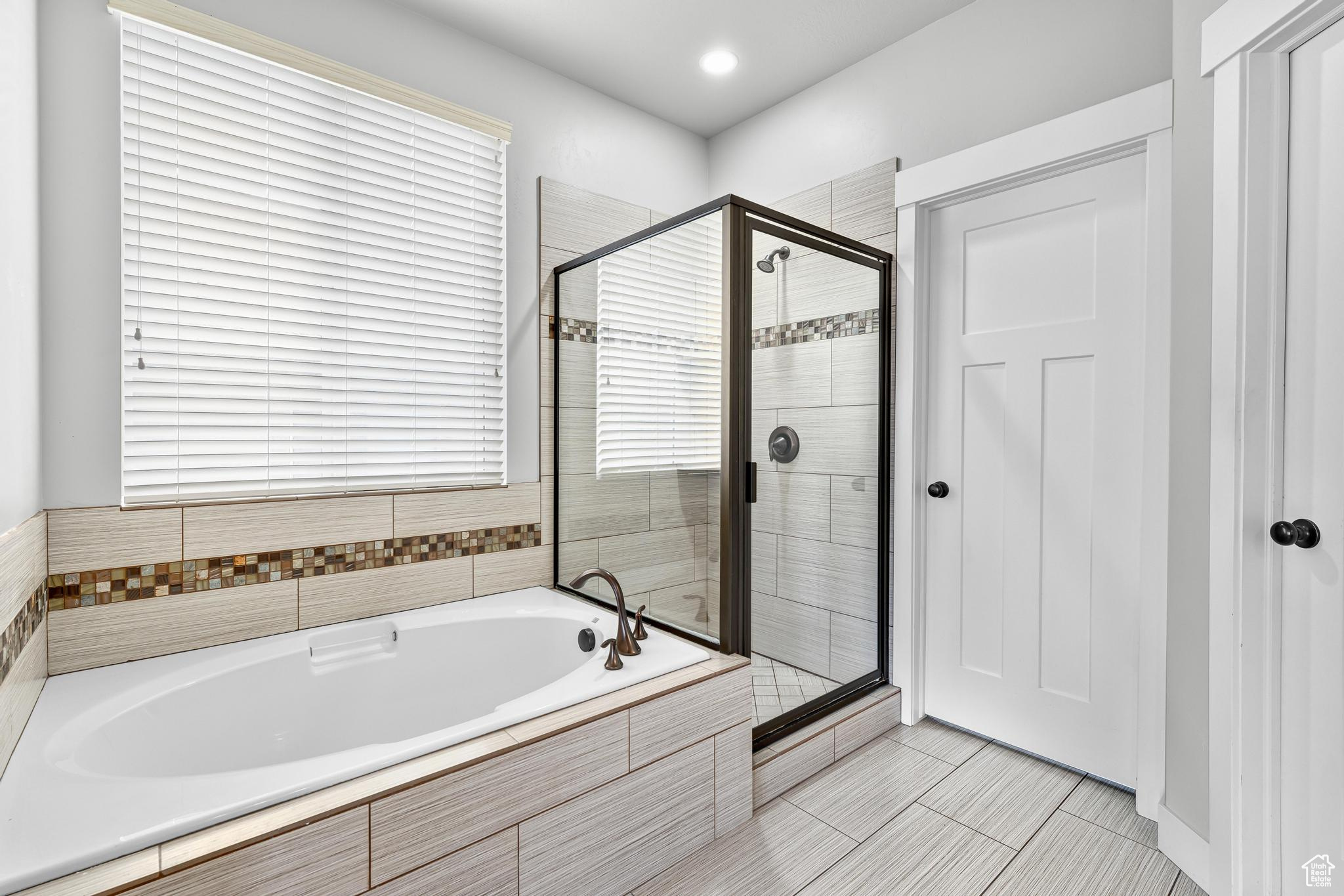 Separate glass enclosed shower and tub.  Fully tiled surround with decorative strip