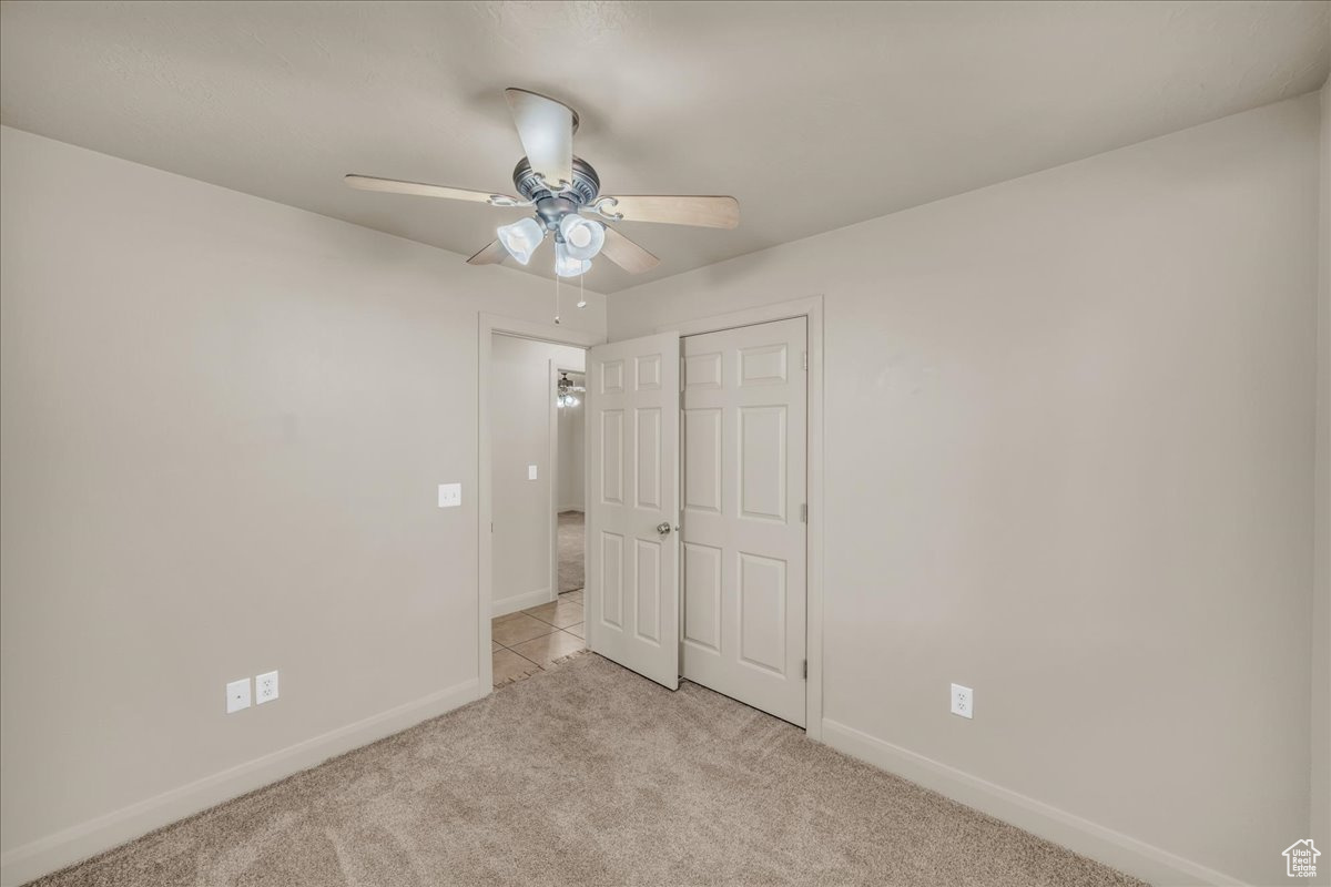 Unfurnished bedroom with ceiling fan, light colored carpet, and a closet