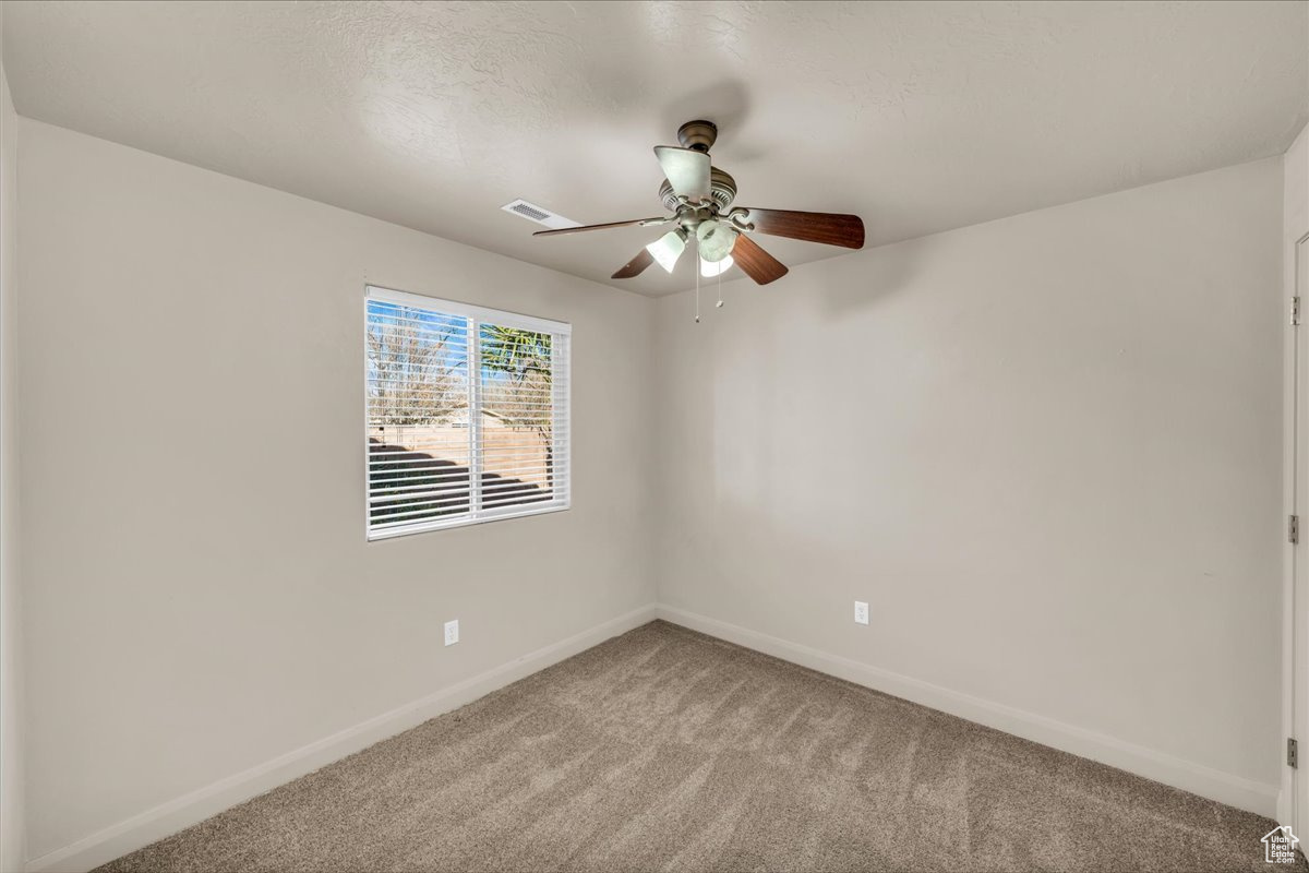 Carpeted spare room featuring ceiling fan