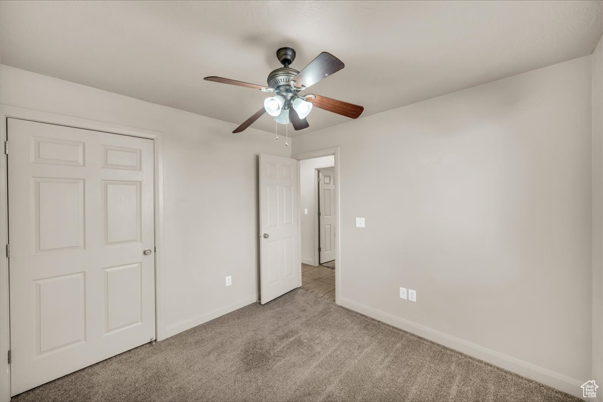 Unfurnished bedroom with ceiling fan and light colored carpet