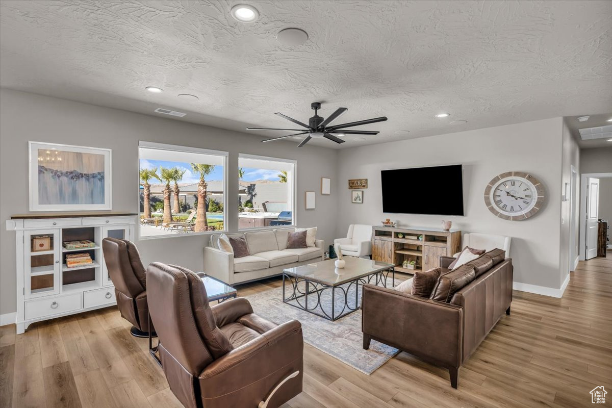 Living room featuring ceiling fan, a textured ceiling, and light hardwood / wood-style floors