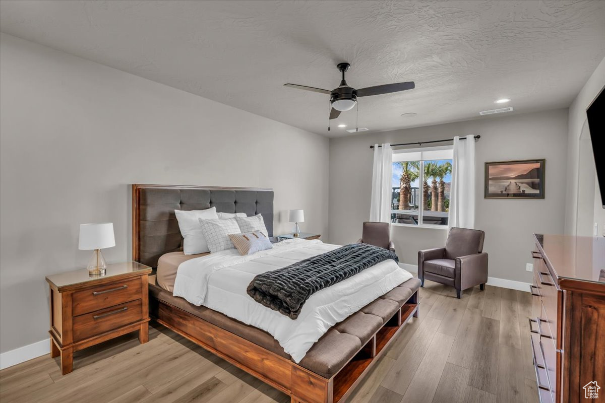 Bedroom with ceiling fan, a textured ceiling, and light wood-type flooring