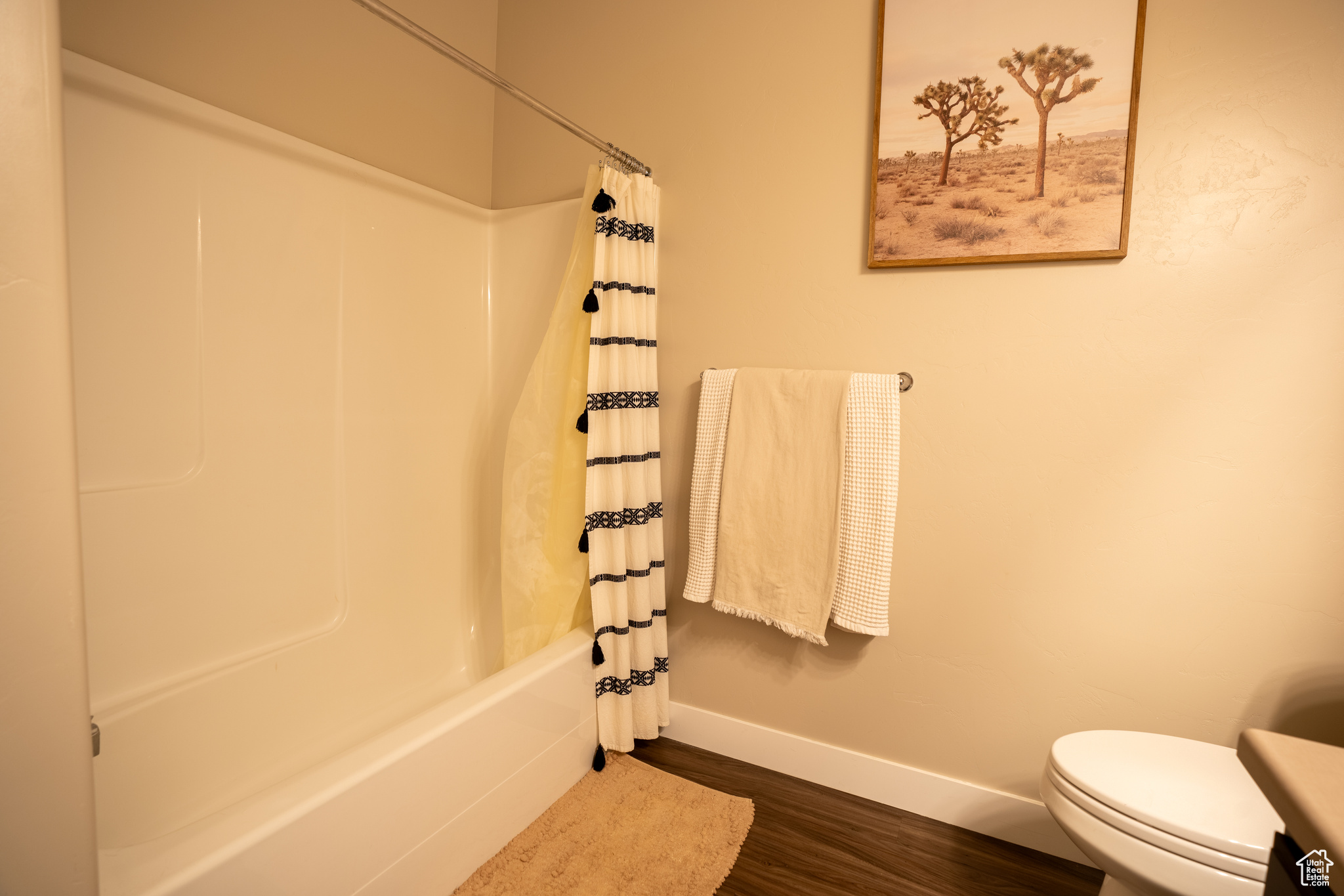 Bathroom featuring hardwood / wood-style floors, shower / bath combination with curtain, and toilet