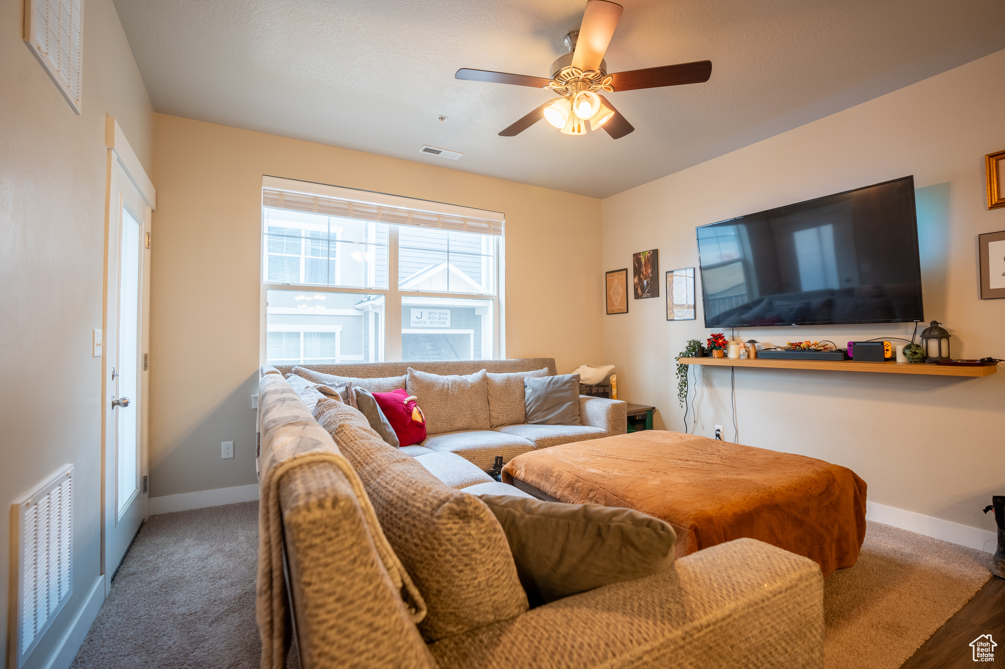 Carpeted living room featuring ceiling fan