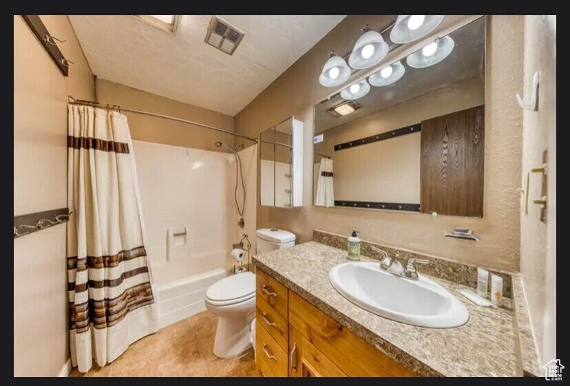 Full bathroom with shower / tub combo with curtain, vanity, tile patterned flooring, and toilet