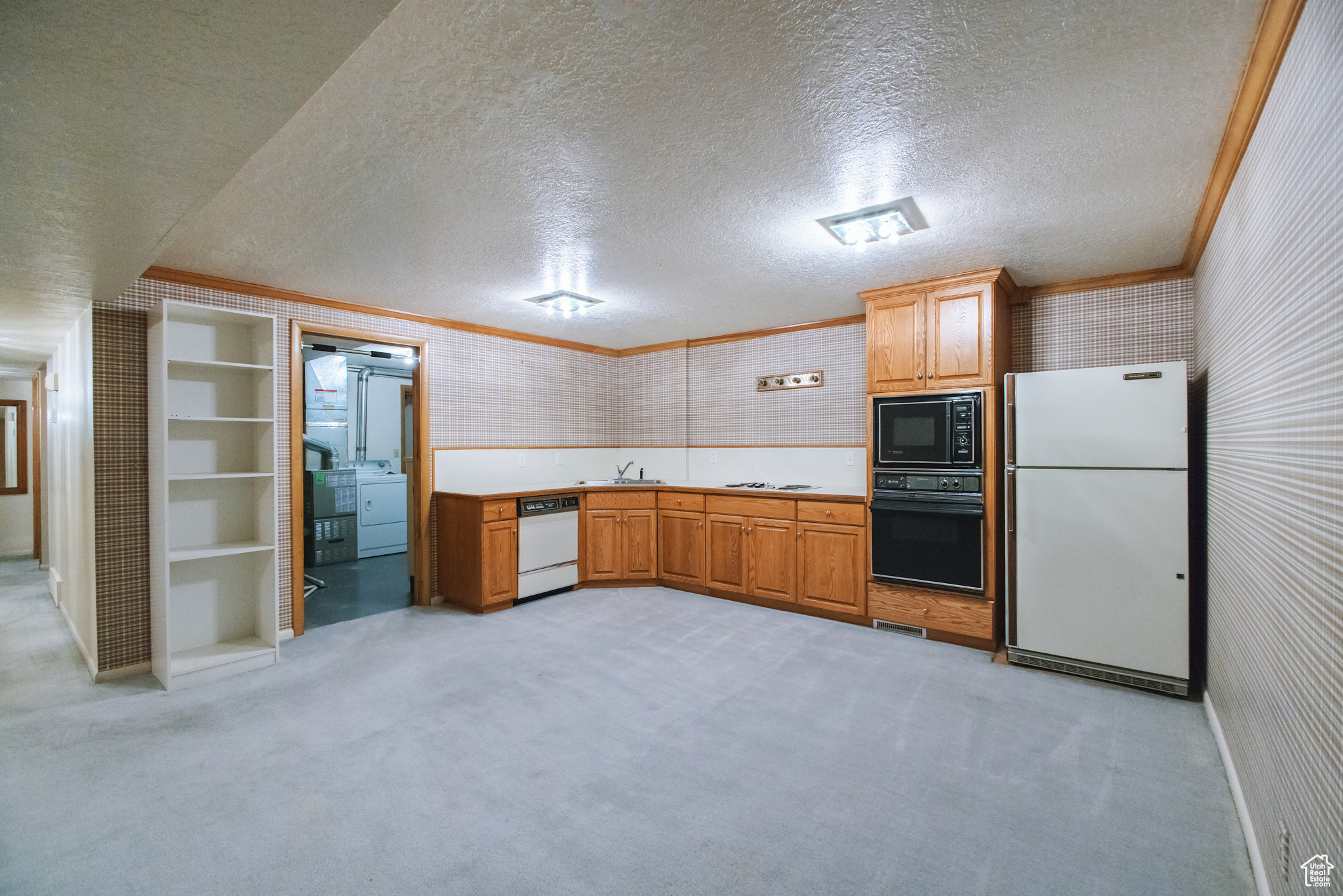 Kitchen featuring crown molding, light colored carpet, washer / dryer, and black appliances