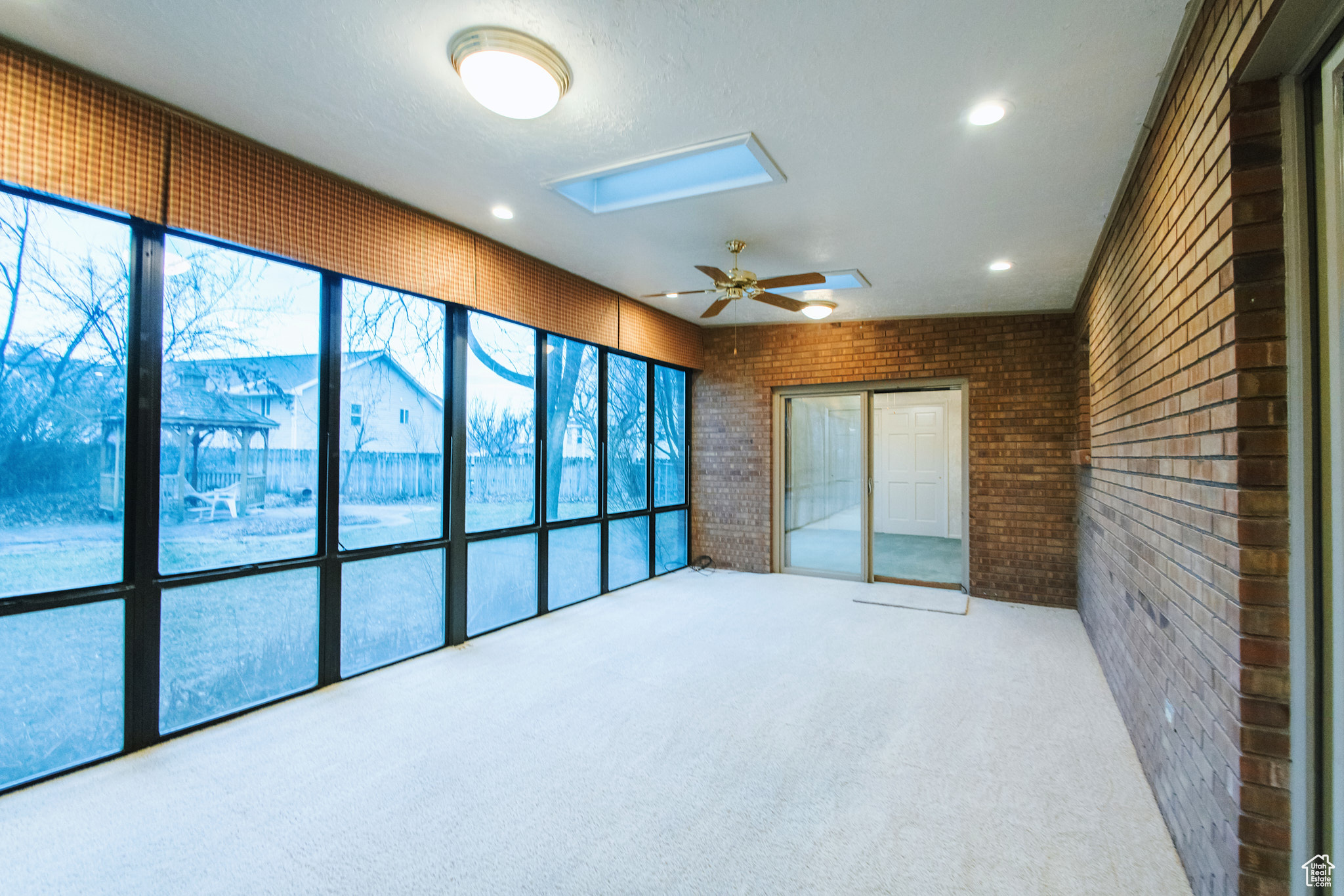 Unfurnished sunroom featuring ceiling fan