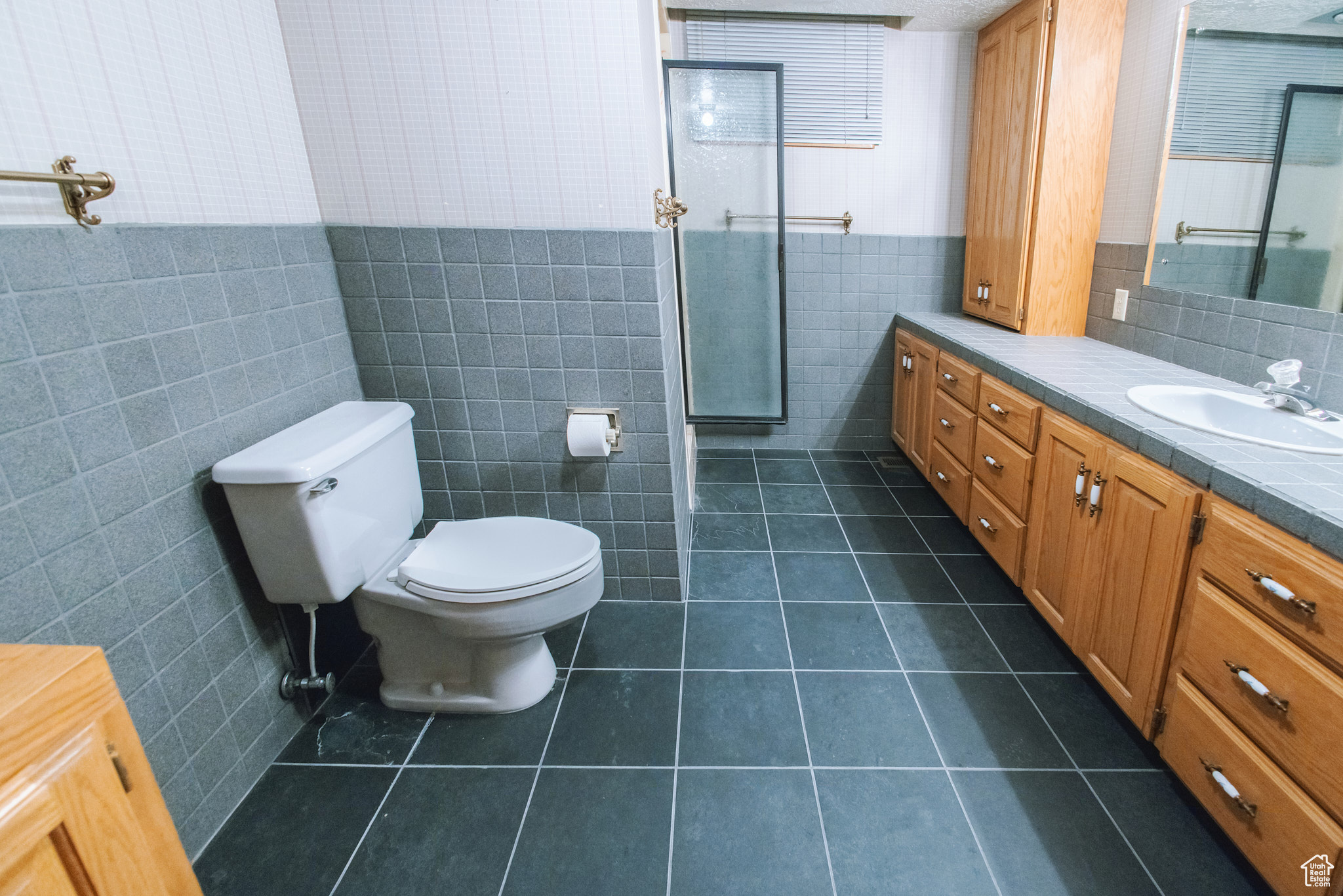 Bathroom featuring tile patterned flooring, vanity, toilet, and tile walls