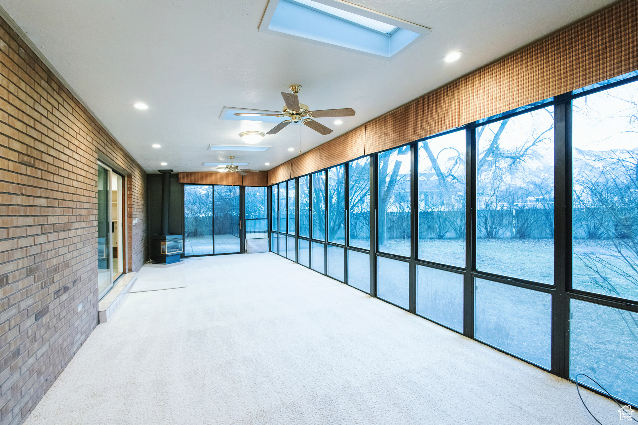 Unfurnished sunroom with ceiling fan and a skylight