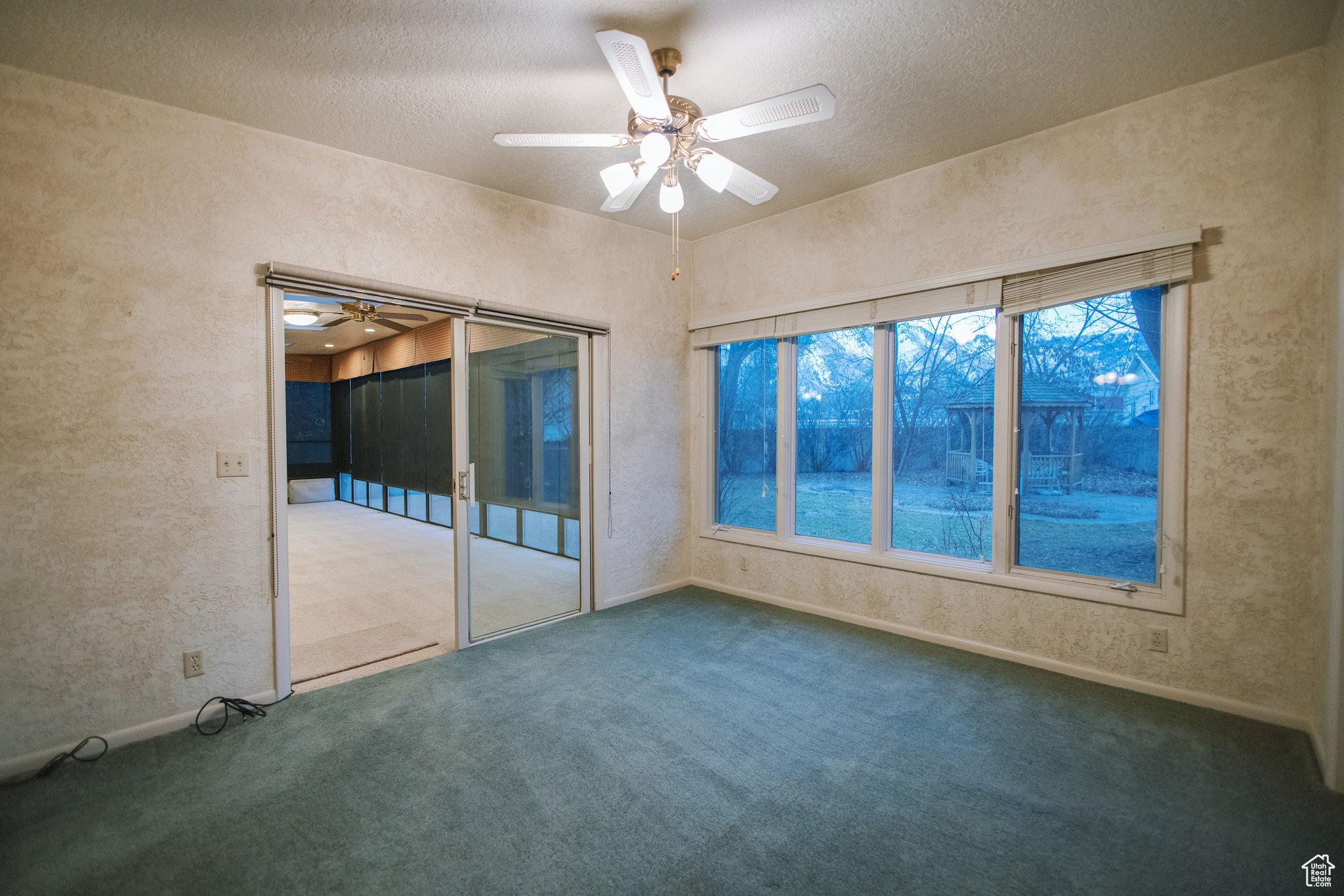 Carpeted empty room featuring a textured ceiling and ceiling fan