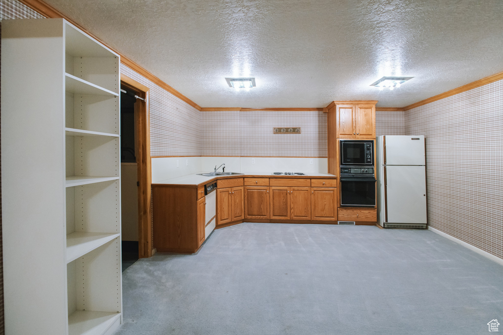 Kitchen featuring ornamental molding, sink, light carpet, and black appliances