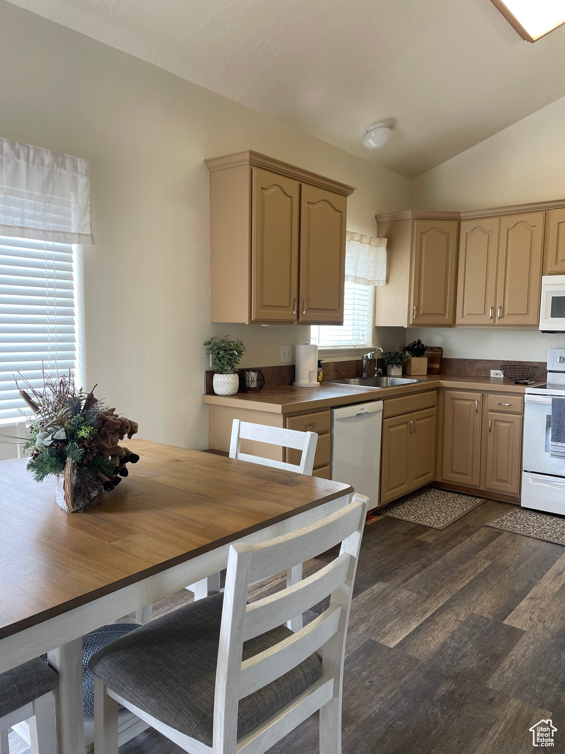 Kitchen featuring sink, white appliances, dark hardwood / wood-style flooring, vaulted ceiling, and light brown cabinets