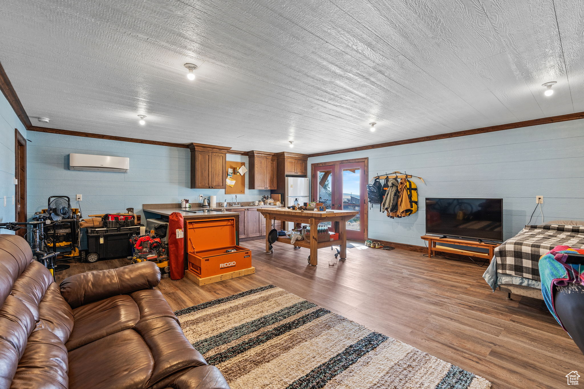 Living room with ornamental molding, an AC wall unit, and hardwood / wood-style floors