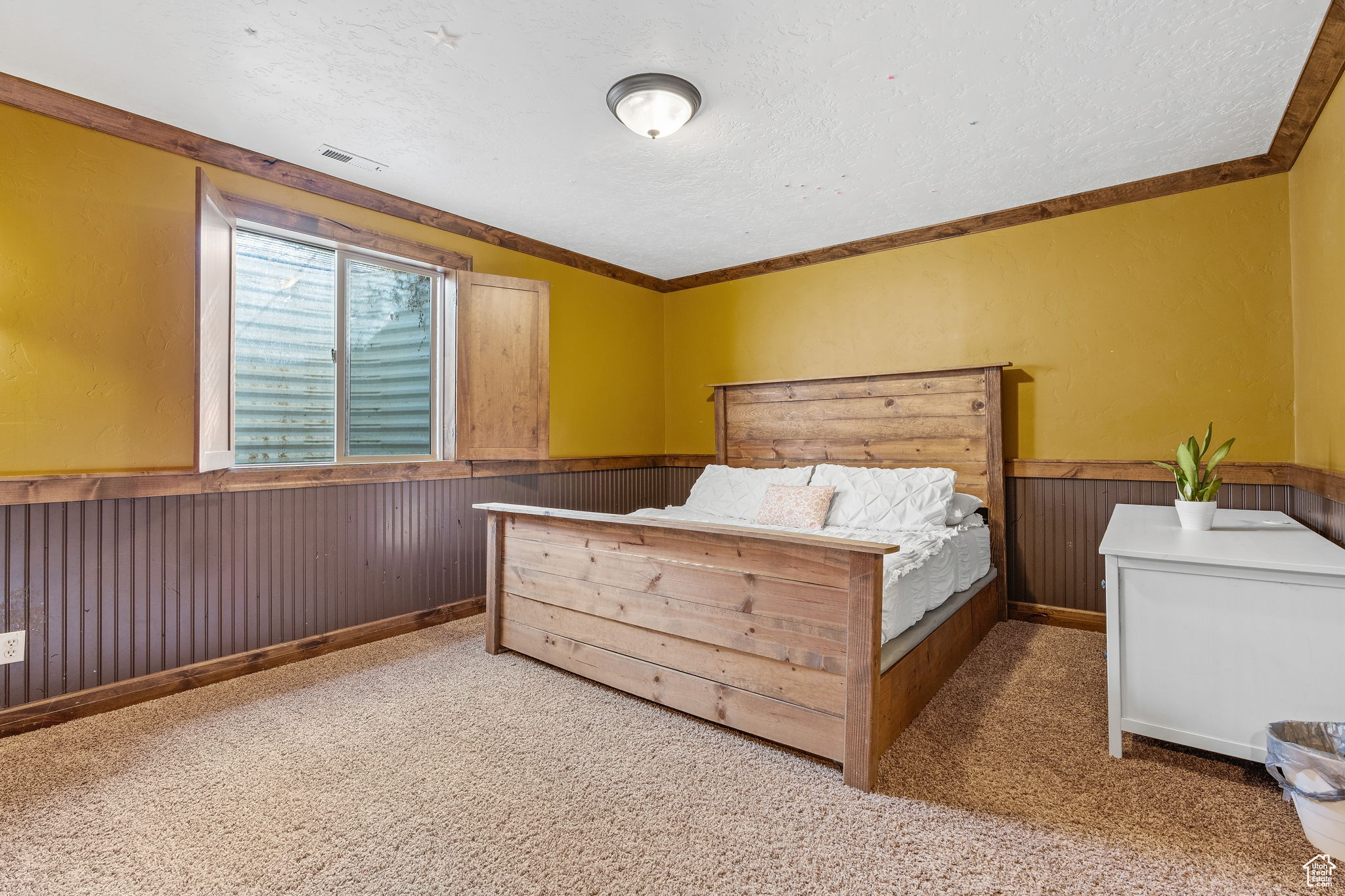 Bedroom featuring crown molding, carpet flooring, a textured ceiling, and wood walls