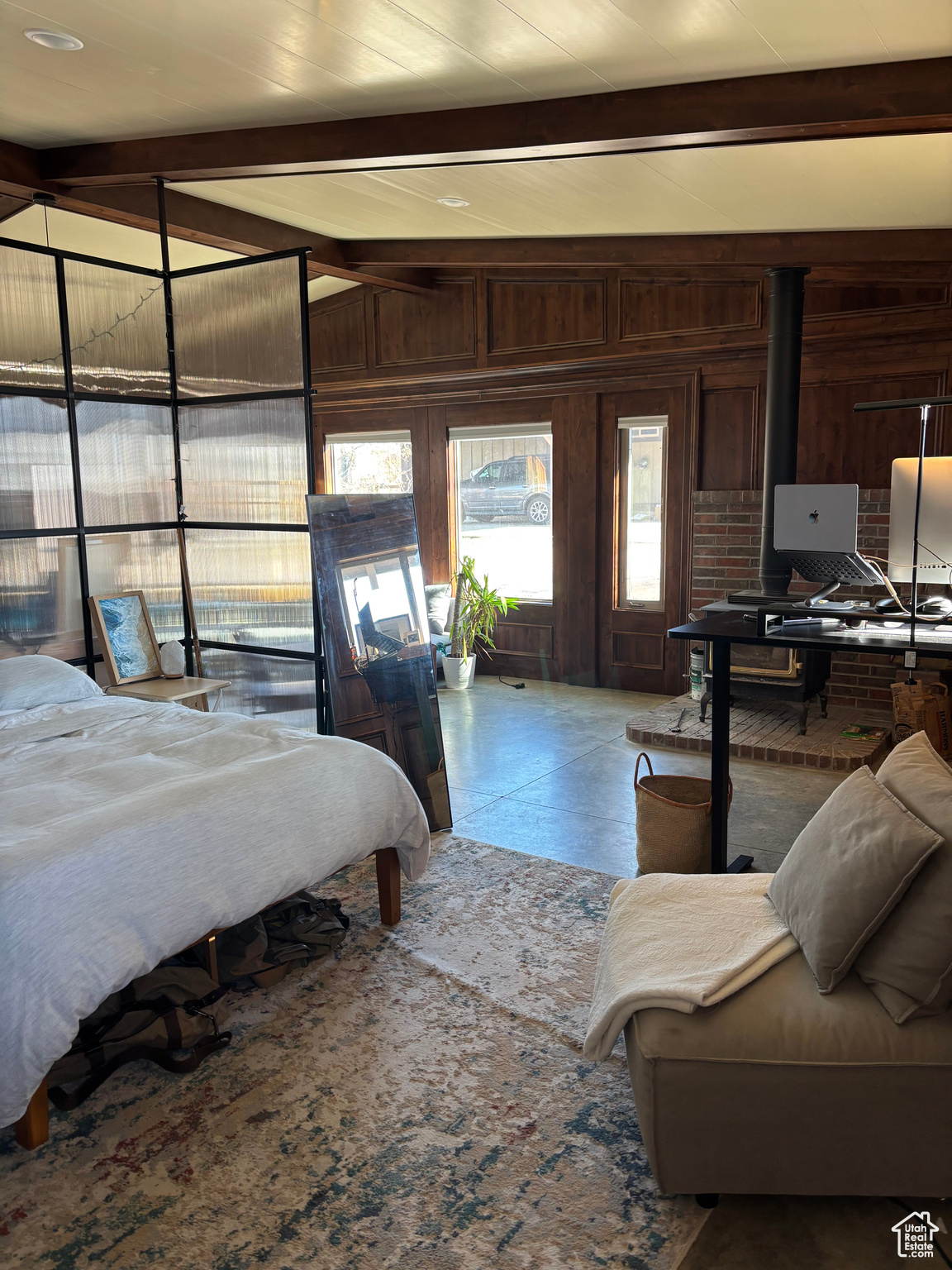 Bedroom with lofted ceiling with beams and wood walls