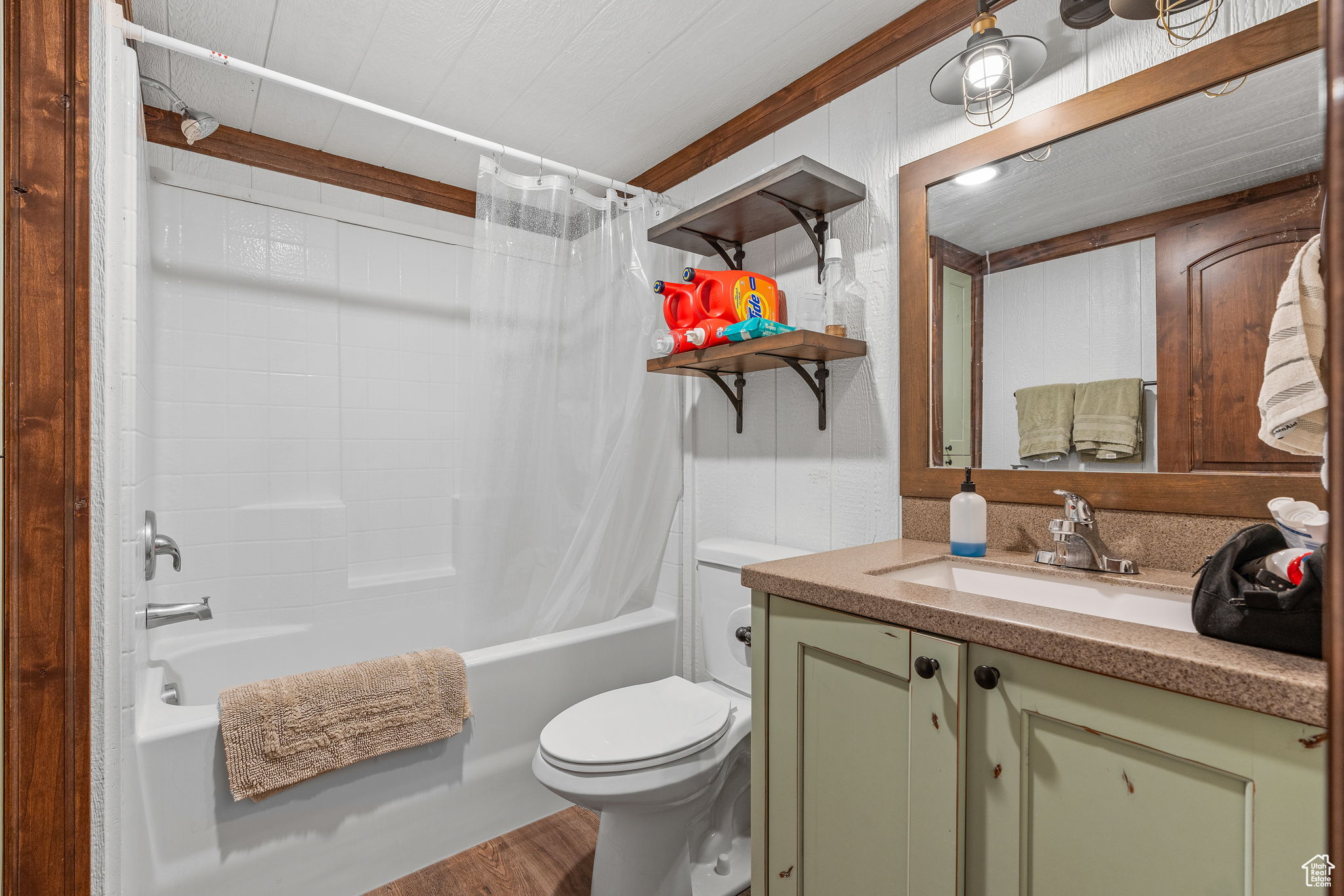 Full bathroom with vanity, wood-type flooring, shower / bathtub combination with curtain, and toilet