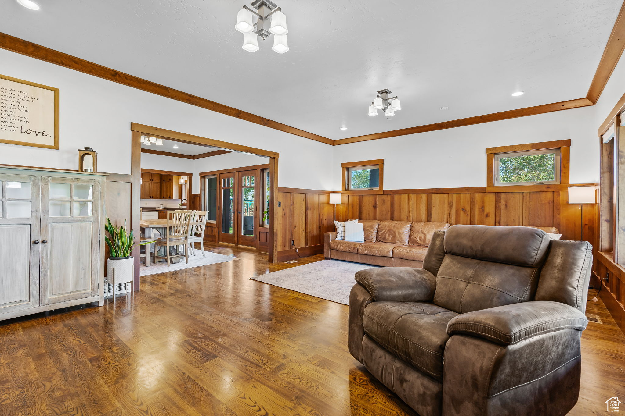 Living room with hardwood / wood-style flooring, ornamental molding, an inviting chandelier, and french doors
