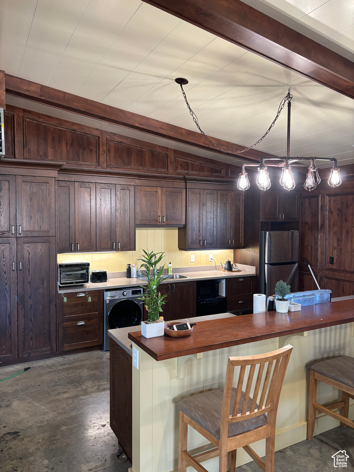Kitchen with pendant lighting, a kitchen breakfast bar, stainless steel fridge, and washer / dryer