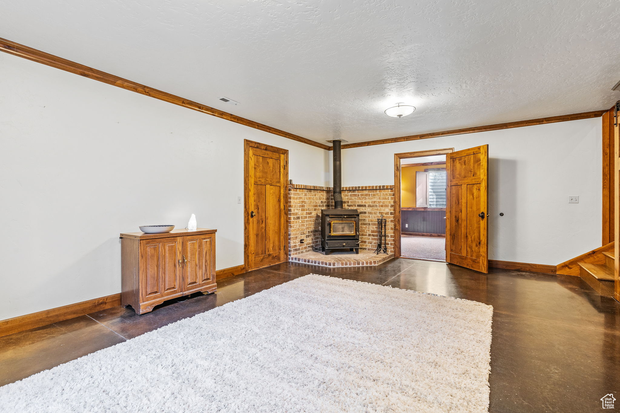 Living room with ornamental molding, a wood stove, and a textured ceiling