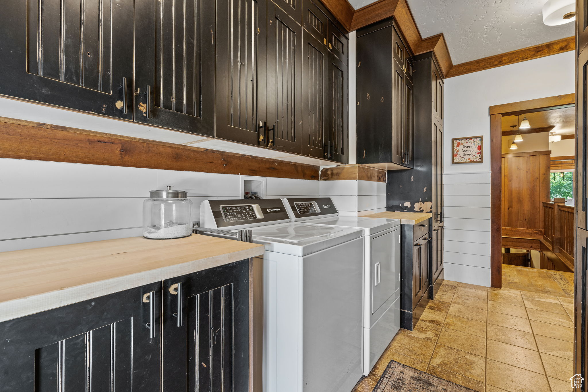 Washroom featuring washing machine and clothes dryer, cabinets, a textured ceiling, ornamental molding, and wooden walls