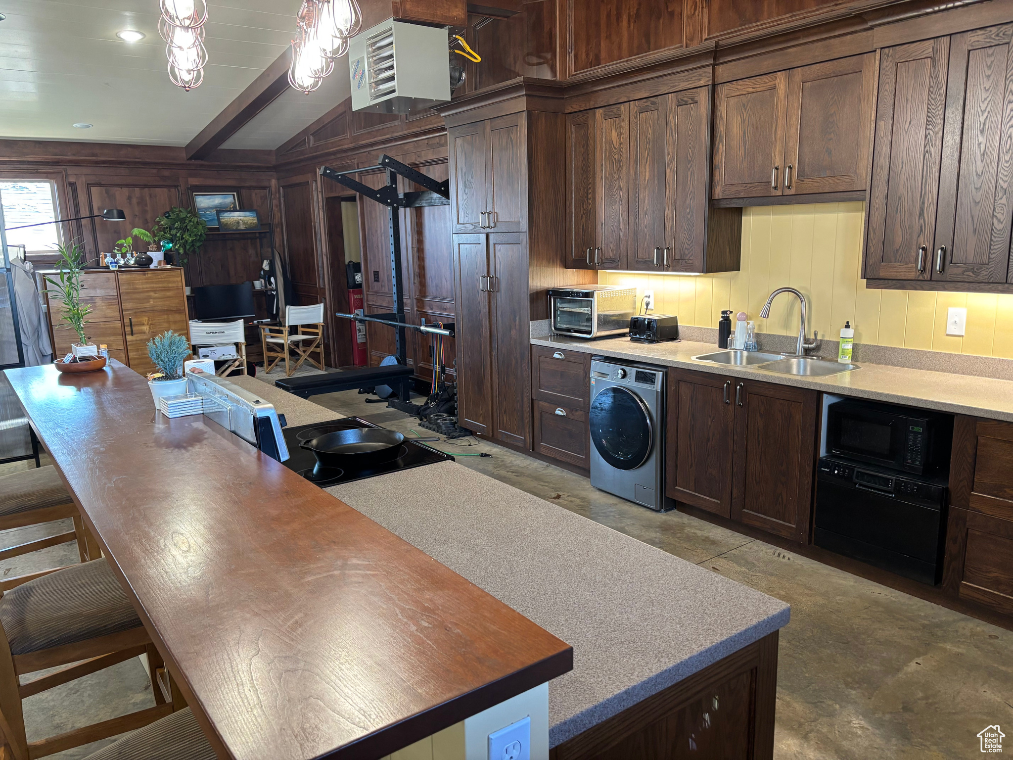 Kitchen featuring dark brown cabinets, washer / dryer, sink, and black microwave