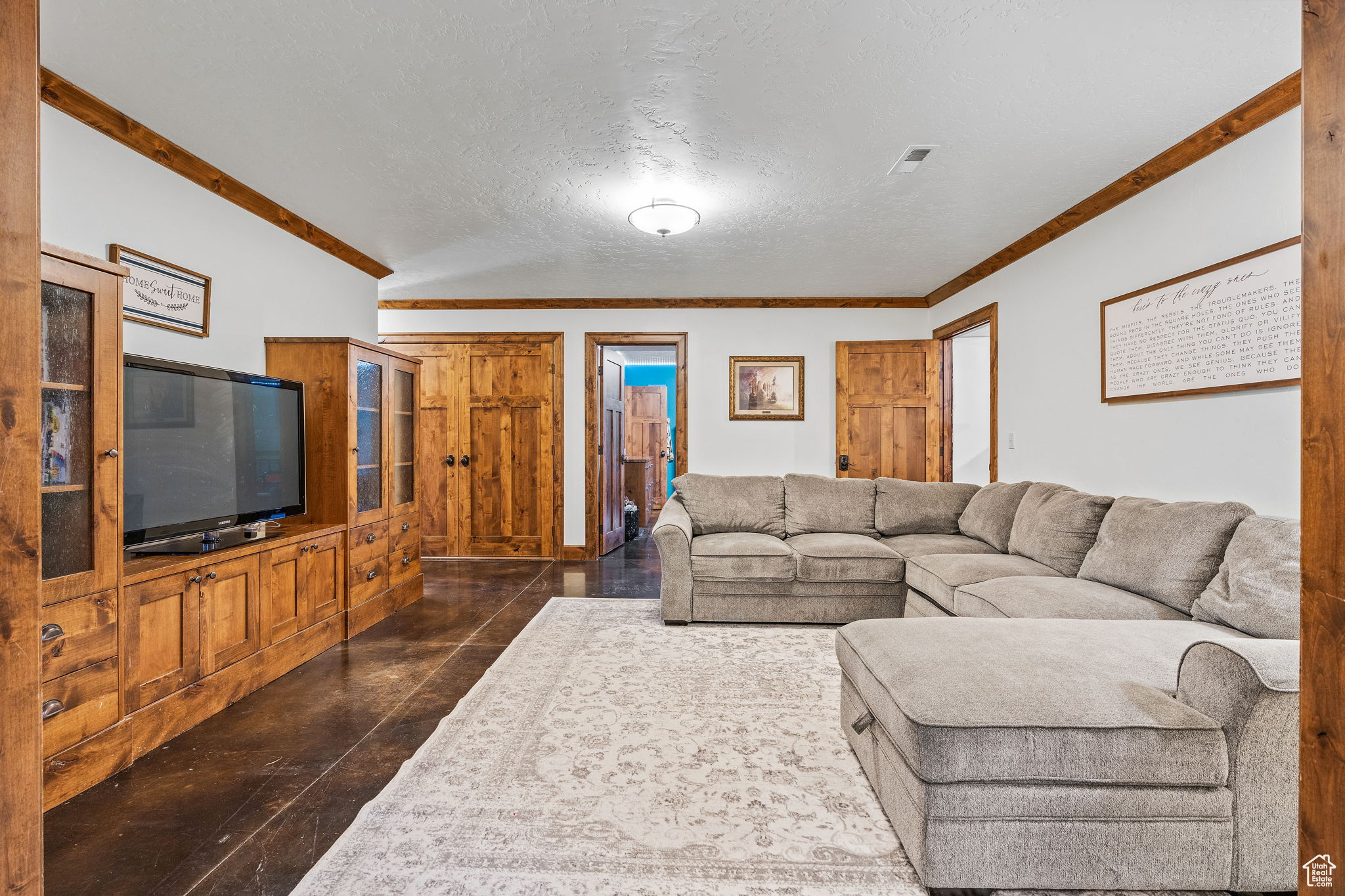 Living room with crown molding, vaulted ceiling, and a textured ceiling