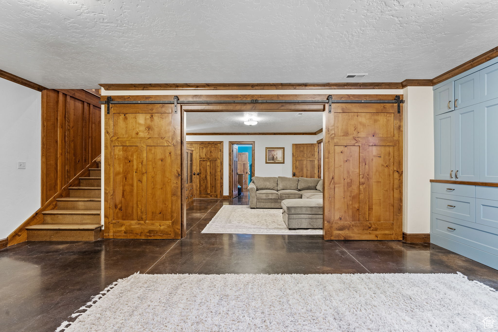 Unfurnished living room with ornamental molding, a barn door, and a textured ceiling