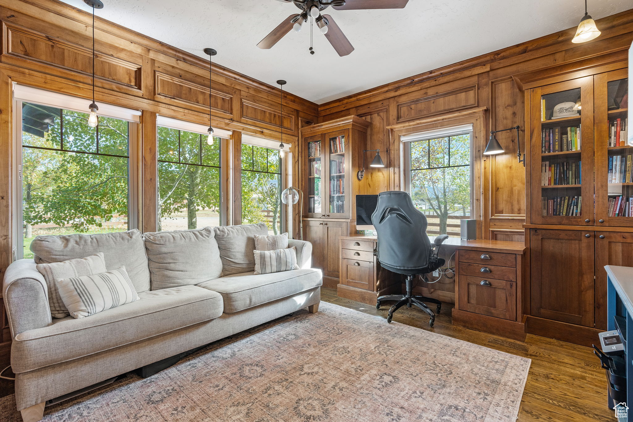 Office with ceiling fan, dark hardwood / wood-style flooring, and wood walls