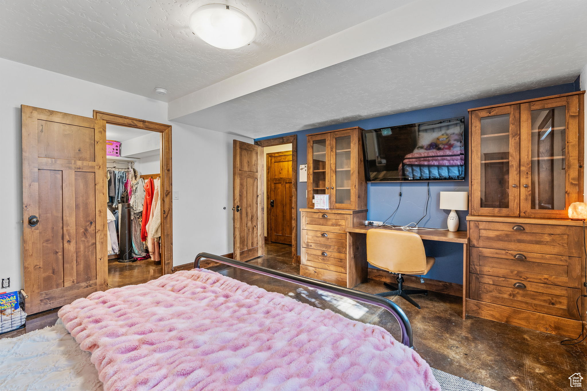 Bedroom with a spacious closet, built in desk, a textured ceiling, and a closet