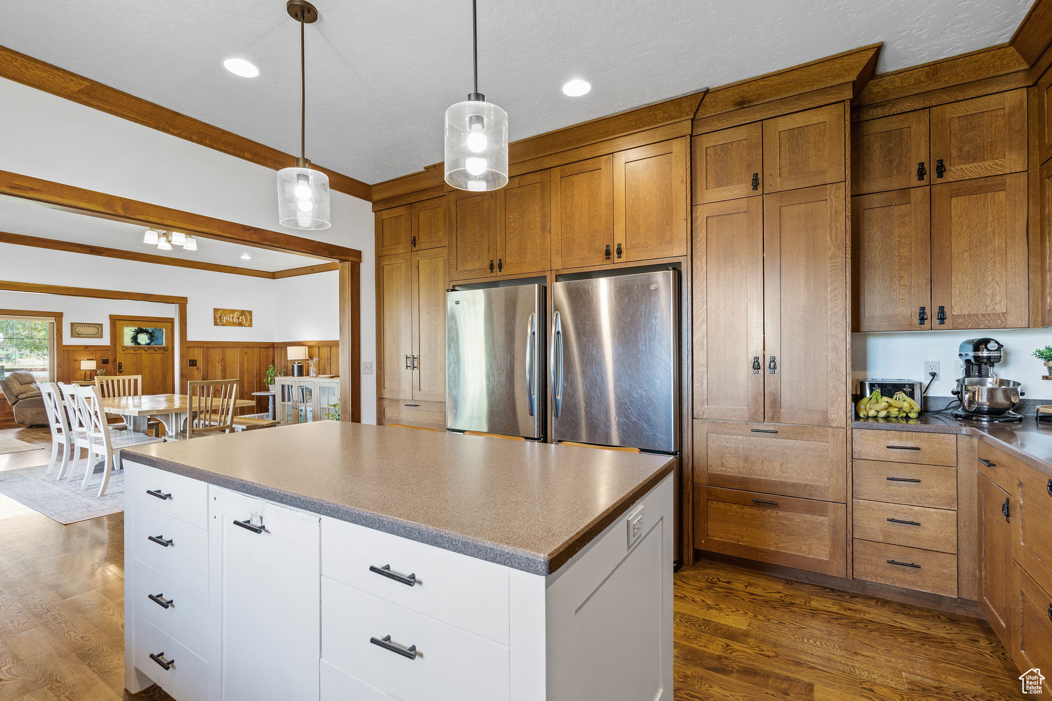 Kitchen with hanging light fixtures, white cabinetry, dark hardwood / wood-style floors, and stainless steel fridge