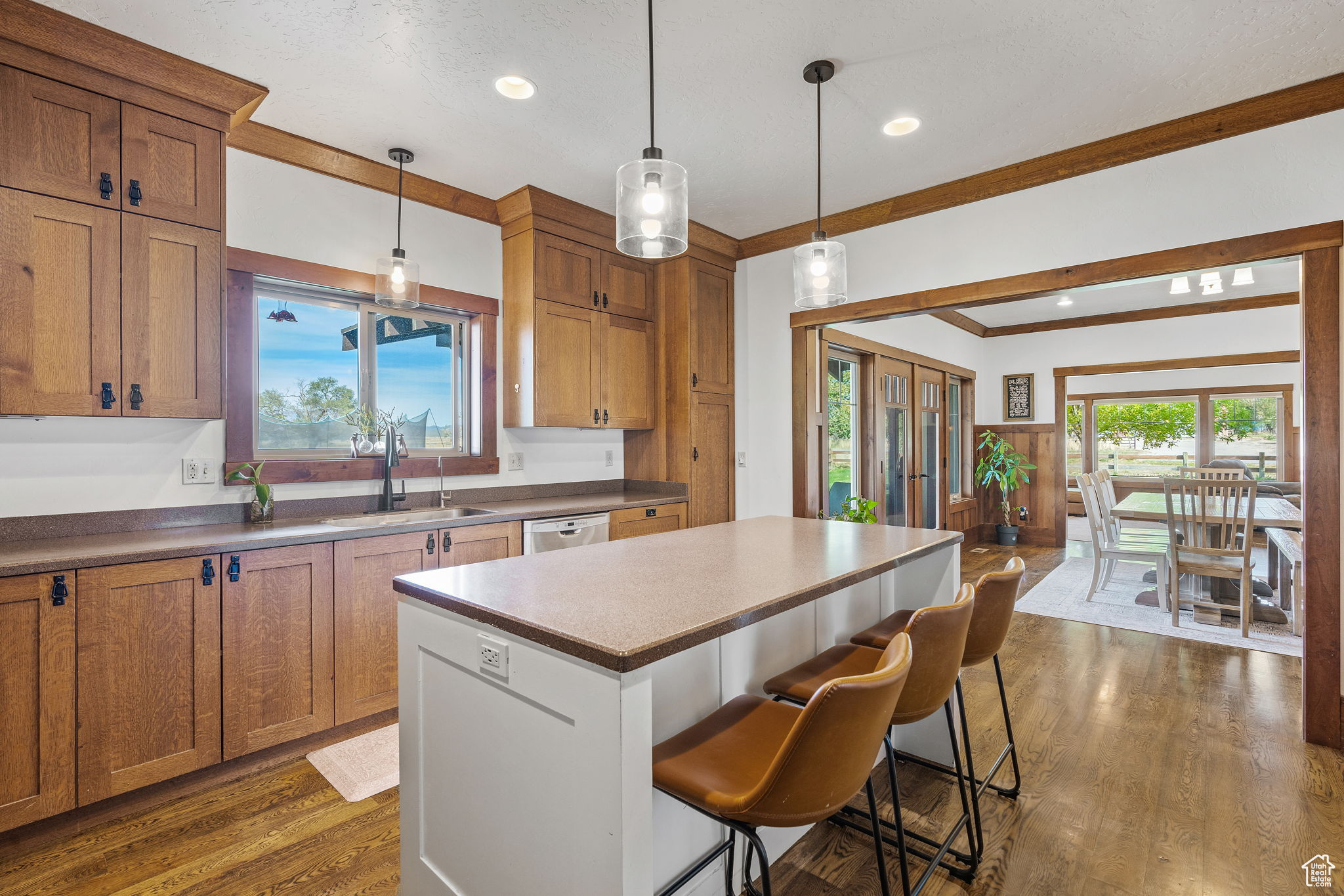 Kitchen with a kitchen island, a breakfast bar, pendant lighting, sink, and dark wood-type flooring